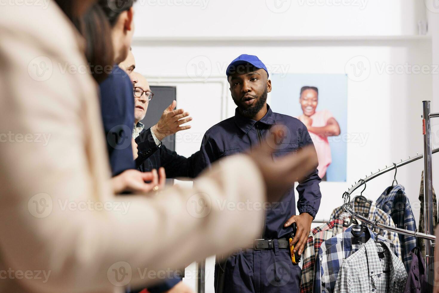 African American man security guard in uniform controlling entrance of fashion store, talking with anxious shoppers wait in line for Black Friday sales. Crowd control during holiday shopping season photo