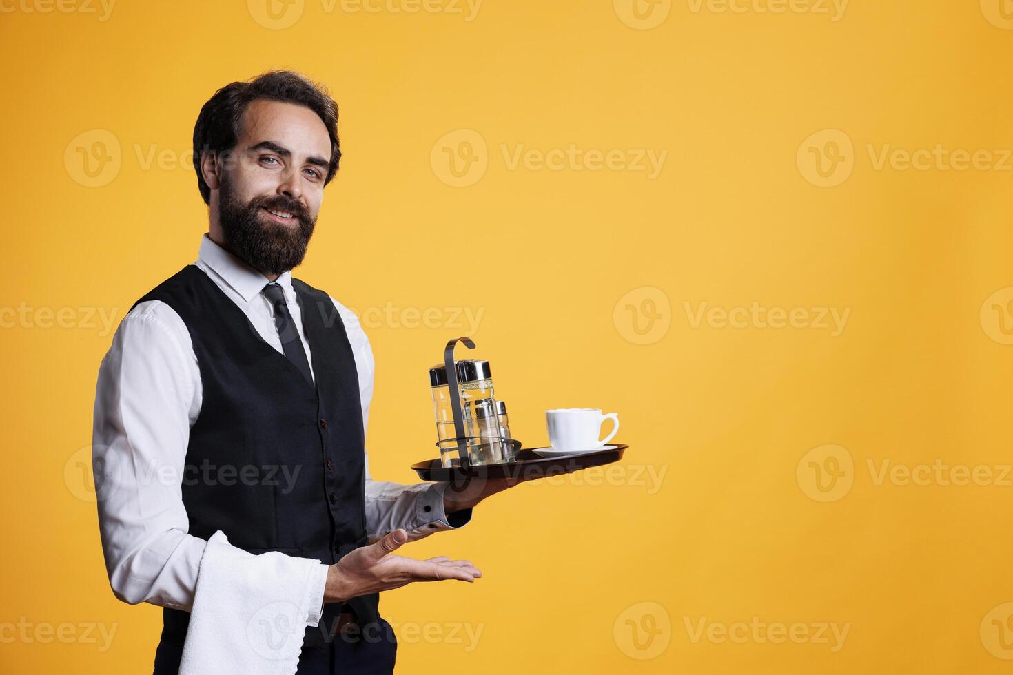 Elegant worker showing marketing ad while he holds platter with coffee cup and accessories. Professional waiter working at restaurant and presenting something to left or right sides. photo