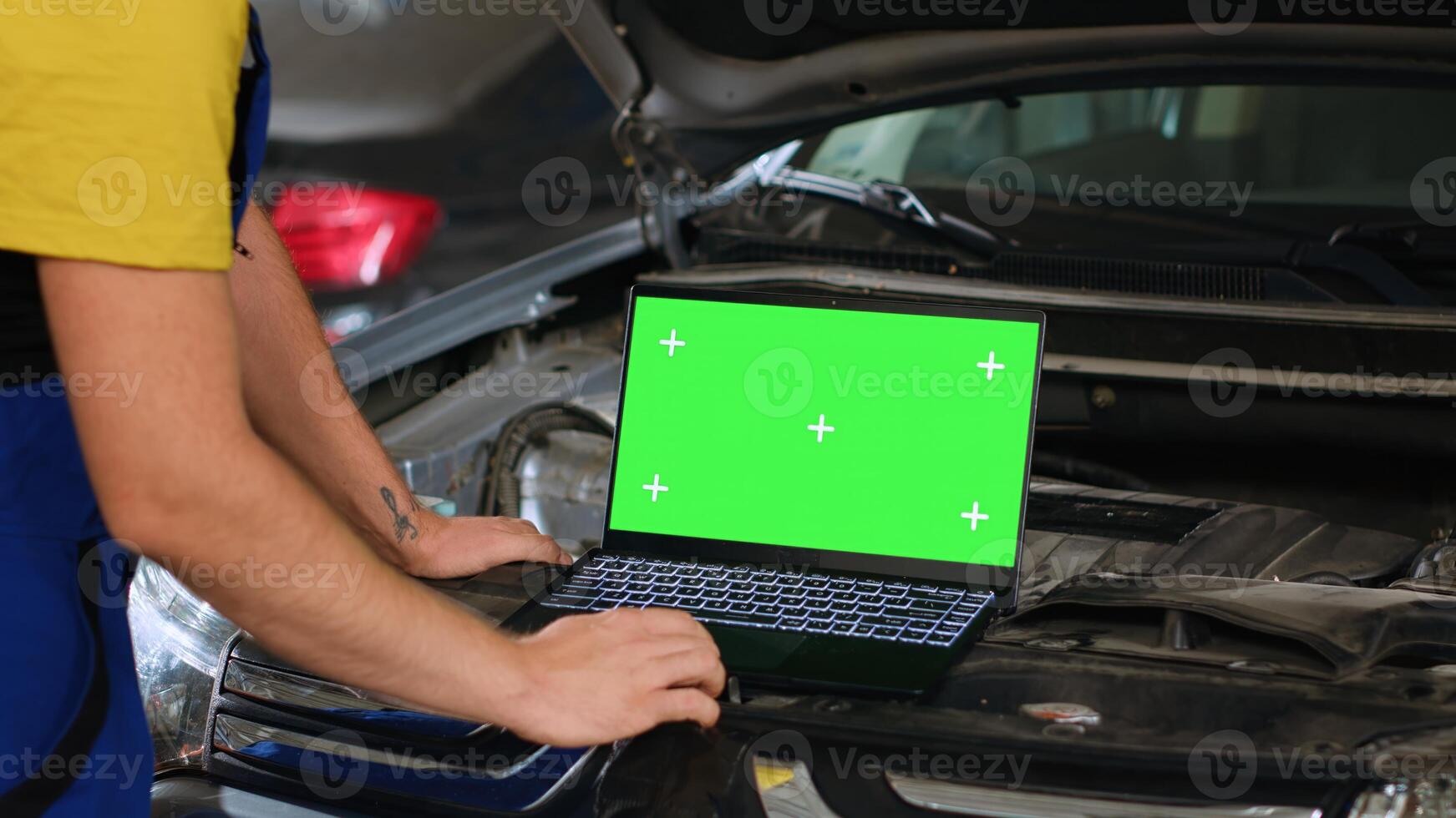 Engineer using green screen laptop in car service to order new parts for damaged vehicle. Close up shot of expert using chroma key device to look online for components to replace old ones photo