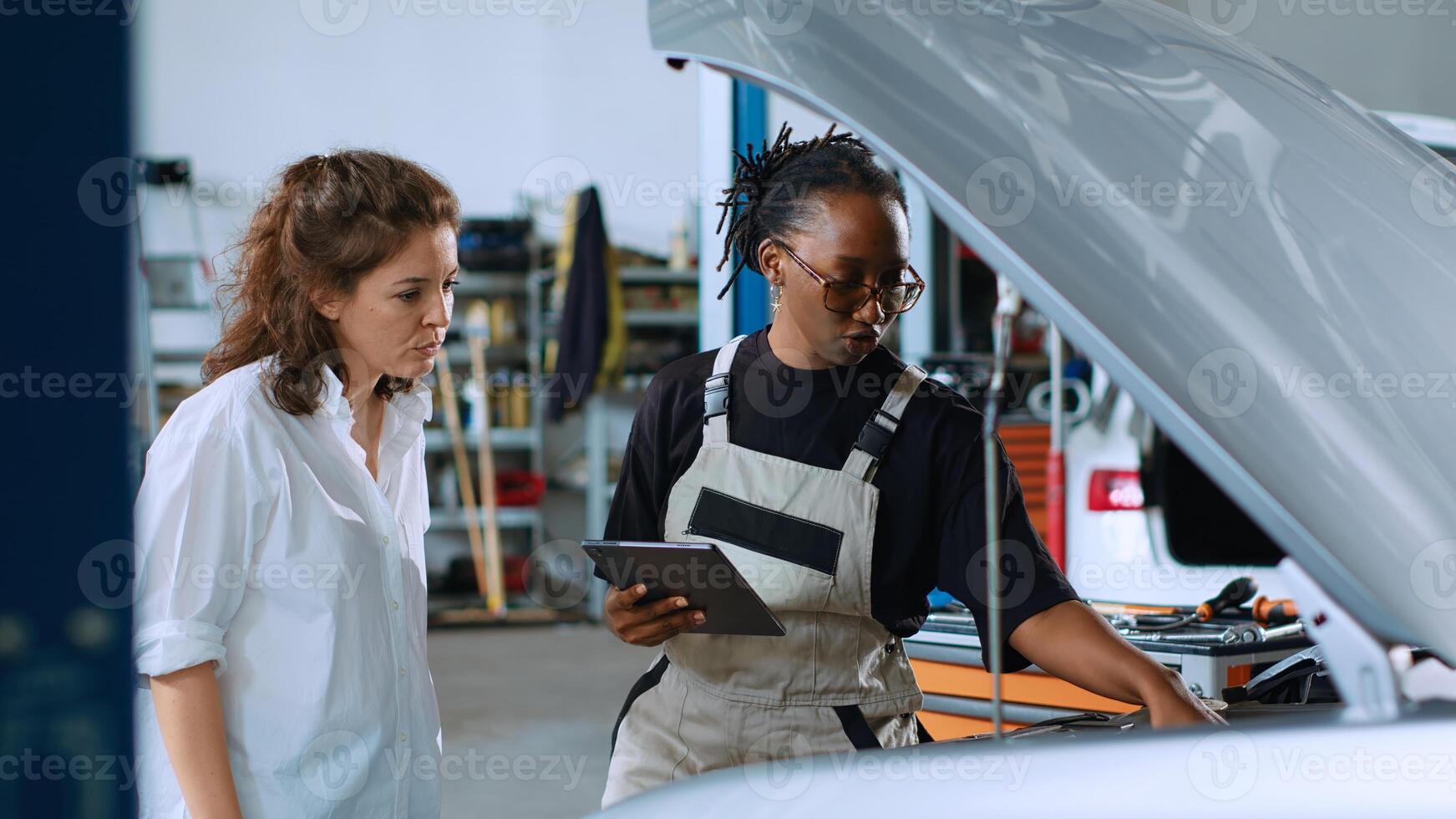 Certified engineer in car service using tablet to calculate repairments invoice for client after fixing malfunctions. Trained professional using device to determine final costs after servicing vehicle photo