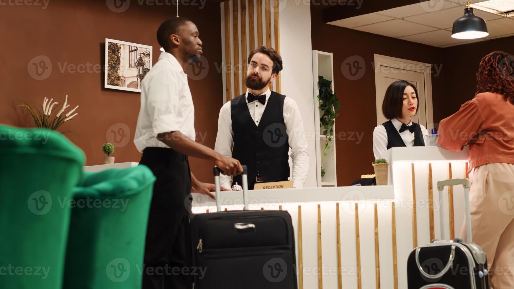 Happy smiling concierge staff team helping tourists with room reservation. Friendly front desk receptionists answering questions about hotel facilities during guests check in process photo