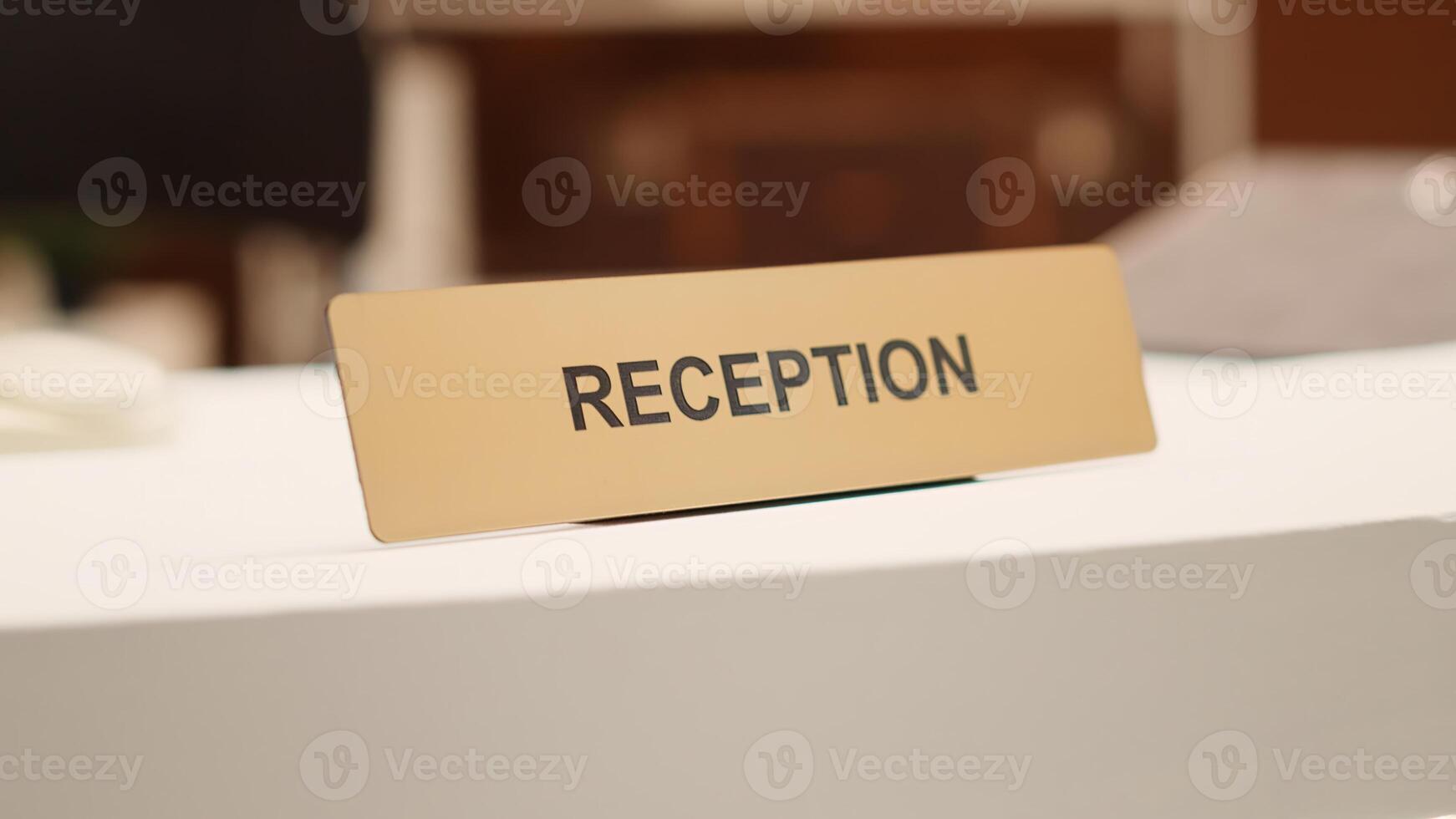 Close up of hotel lobby check in reception plaque sign and folders of tourist accommodation information paperwork. Empty clean desk in stylish resort lounge interior, handheld shot photo