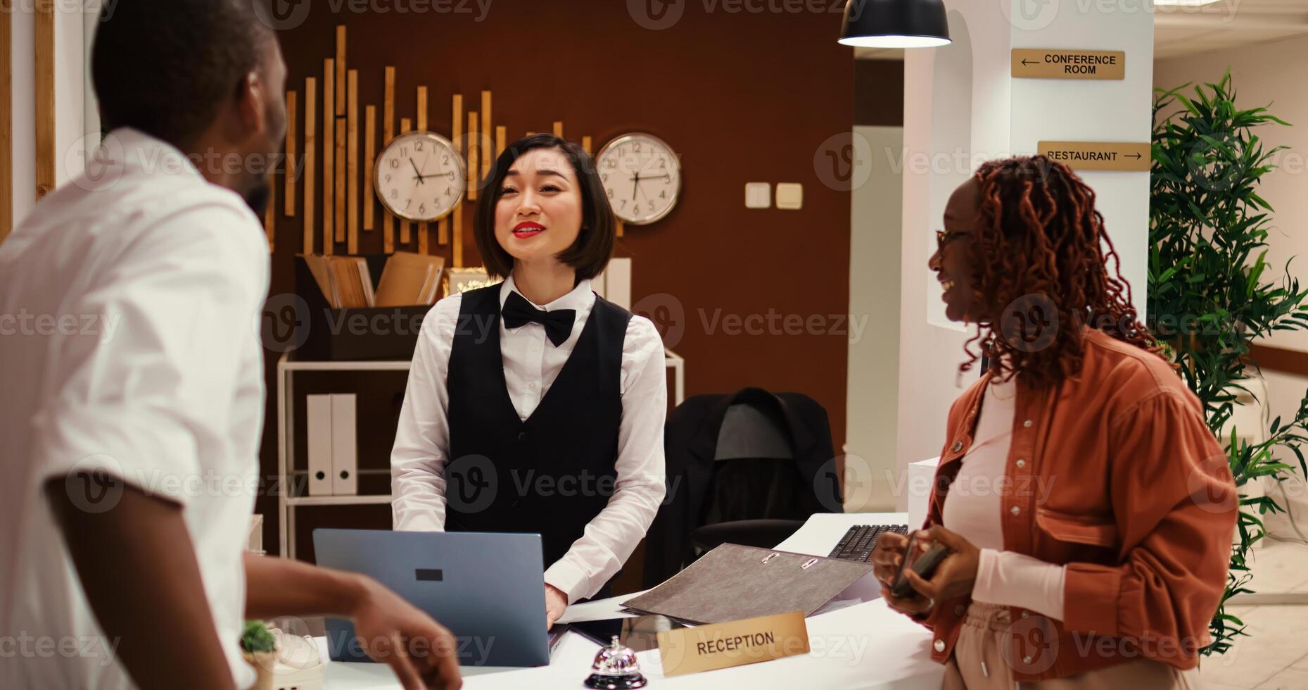 Friendly receptionist presenting holiday package options to african american couple in posh hotel. Husband and wife on honeymoon trip preparing to pay for extra room amenities in resort lounge photo