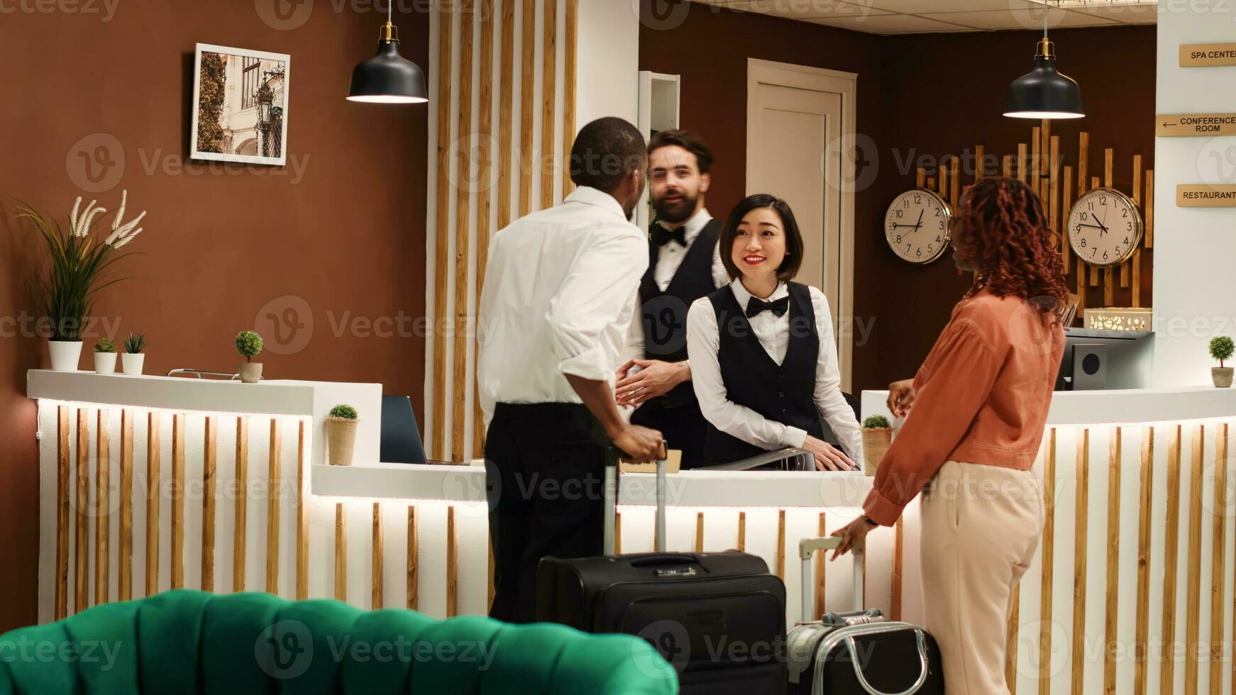 Hotel administrator handing guests booking reservation file to receptionists during check in. Tourists being assisted by friendly concierge staff coworkers inside reception lobby photo