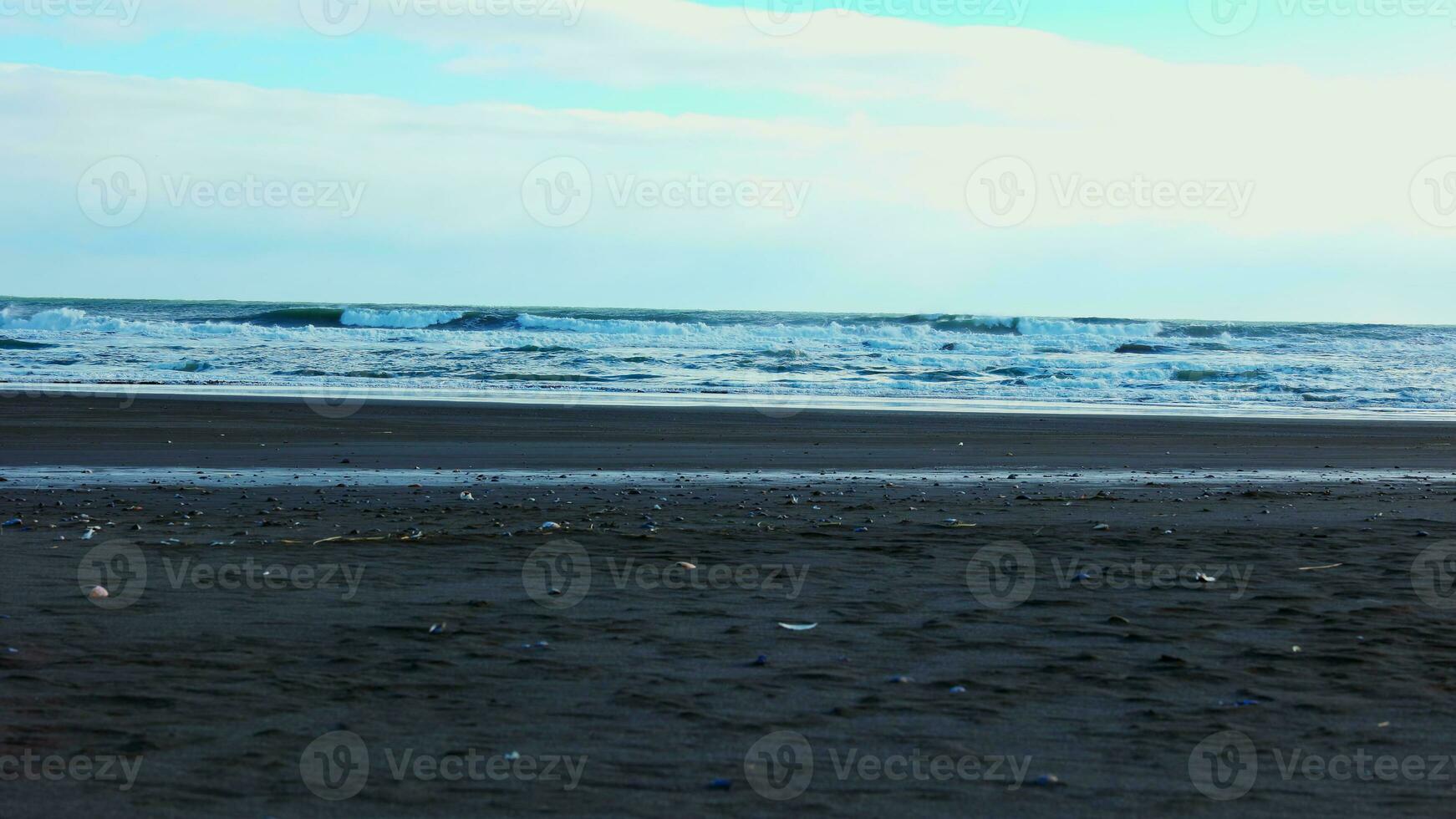 Beautiful nordic black sand beach with waves splashing on atlantic shore coastline, icelandic scenery. Famous stokksnes beach with freezing cold water and strong tides. Handheld shot. photo