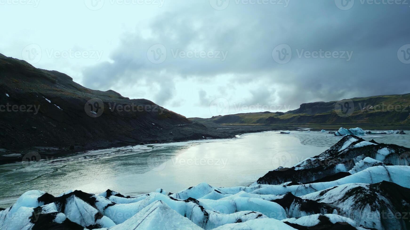 Drone shot of vatnajokull glacier cap in iceland, beautiful ice blocks with massive crevasse around snowy mountains. Majestic frosty icebergs floating on frozen lake. Slow motion. photo