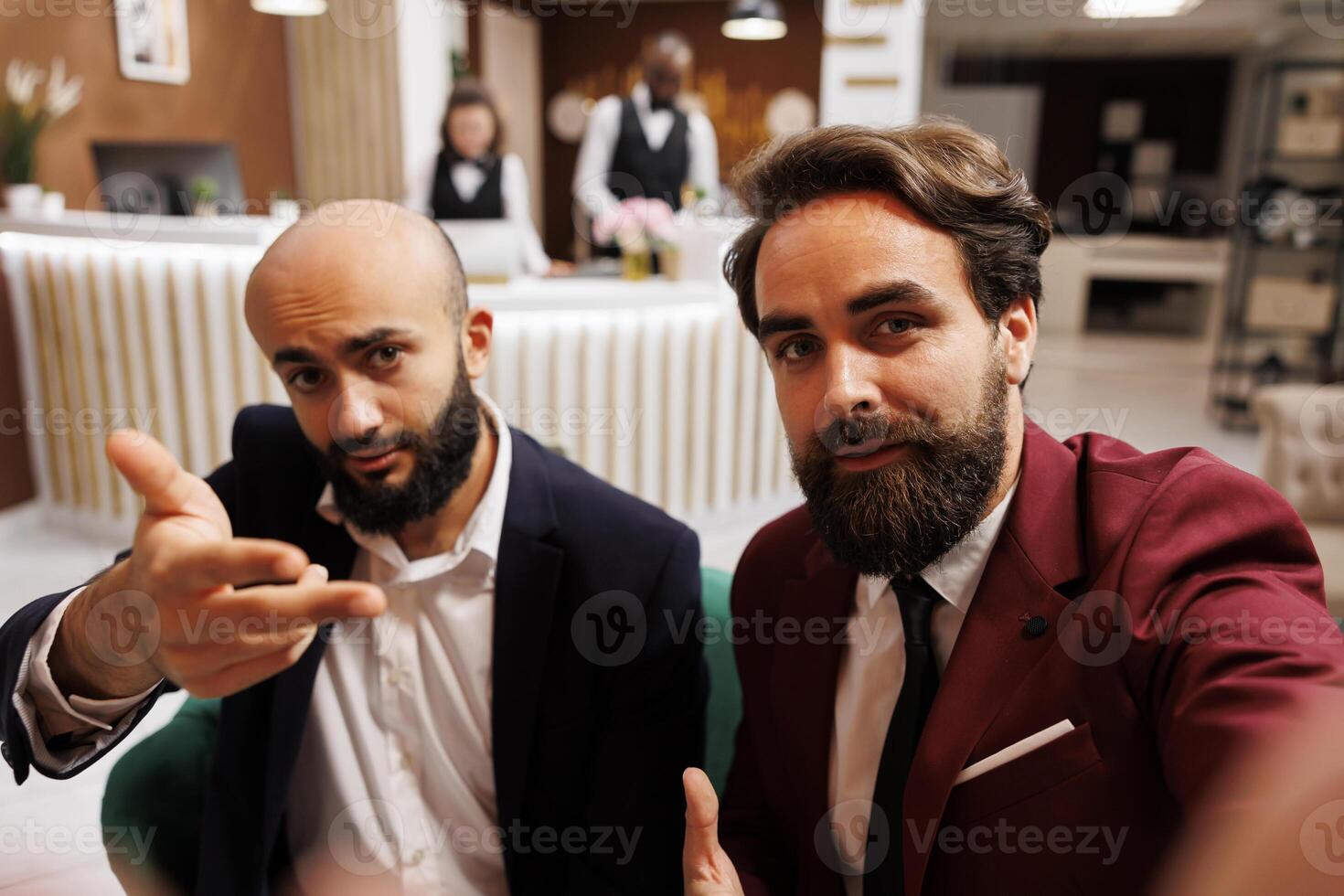 POV of diverse men in hotel lobby, meeting abroad to create new parnership and collaborate on project. Team of businessmen attend videocall conference together in lounge area. photo