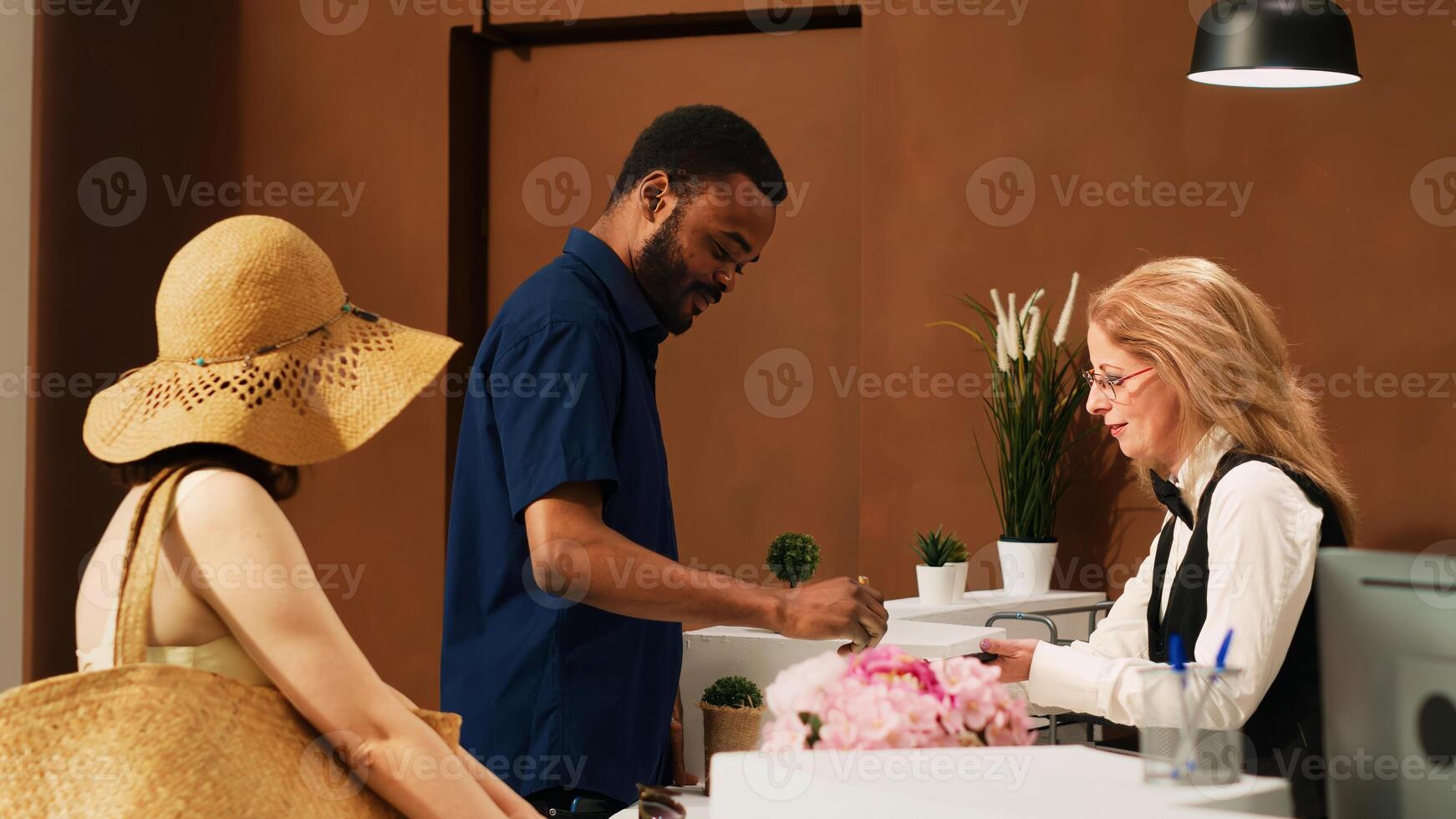 Hotel guests registering at reception, signing electronic check in forms on tablet at tropical resort. People on honeymoon vacation arriving at front desk lobby, hotel concierge. photo