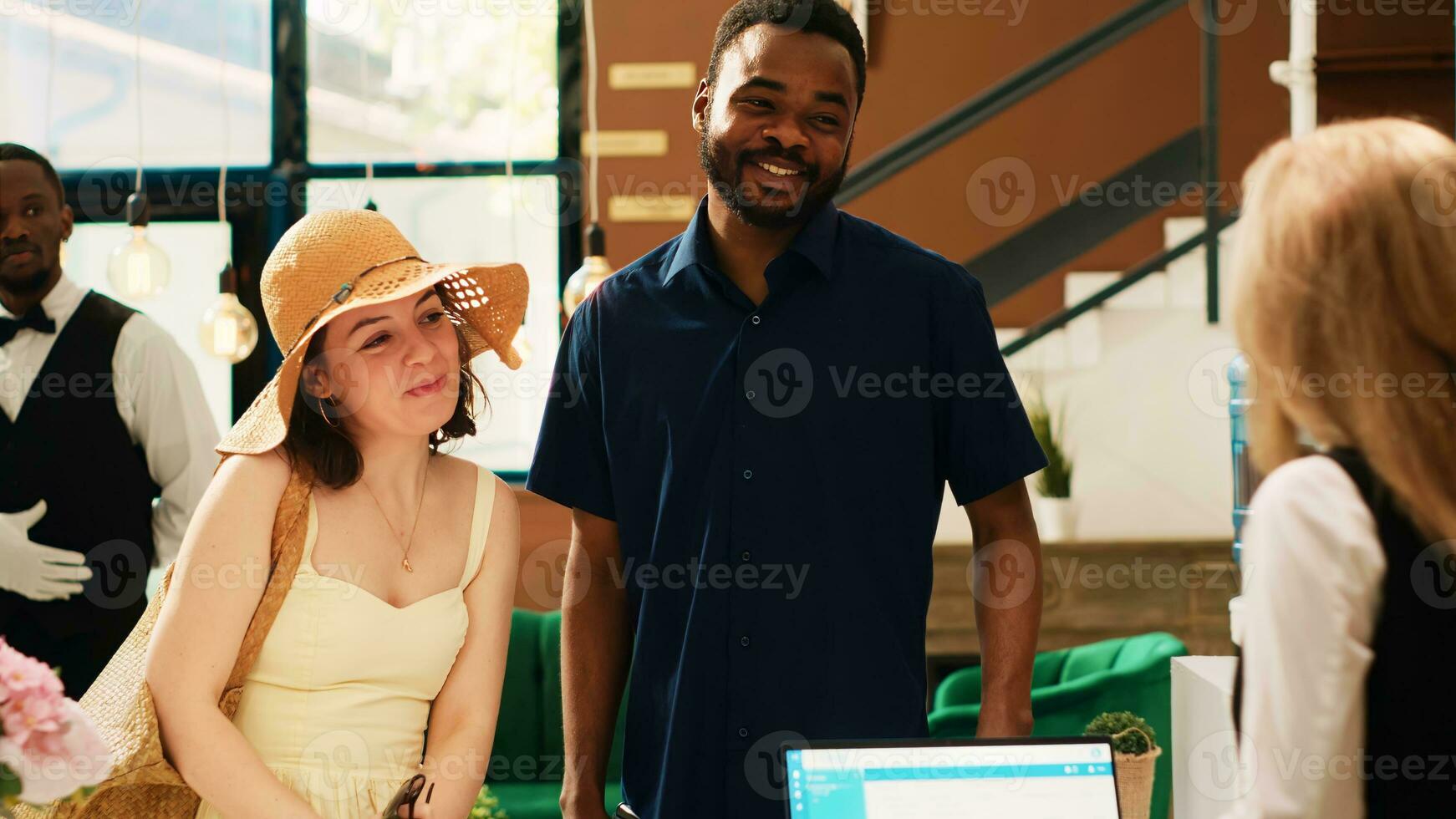 Couple giving access room card to receptionist at front desk, leaving summer tropical resort. Tourists doing checkout process and handing key to hotel concierge, saying goodbye. photo