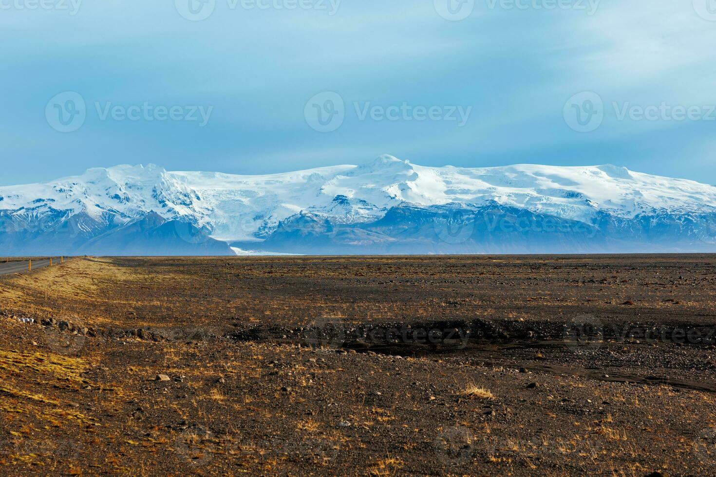 maravilloso tierras altas ver en islandés región, con nieve cubierto montañas y congelado pastos en distancia. borde del camino pintoresco calzada con del Norte paisaje de colinas y campos en Islandia. foto