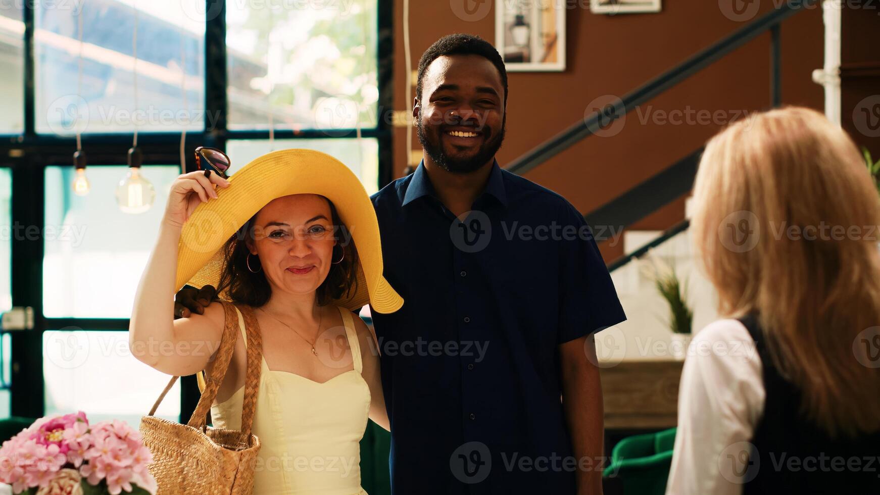 People arriving at luxury tropical hotel, approaching front desk in lobby and preparing to do check in process. Guests on honeymoon trip talking to seaside resort staff about room reservation. photo