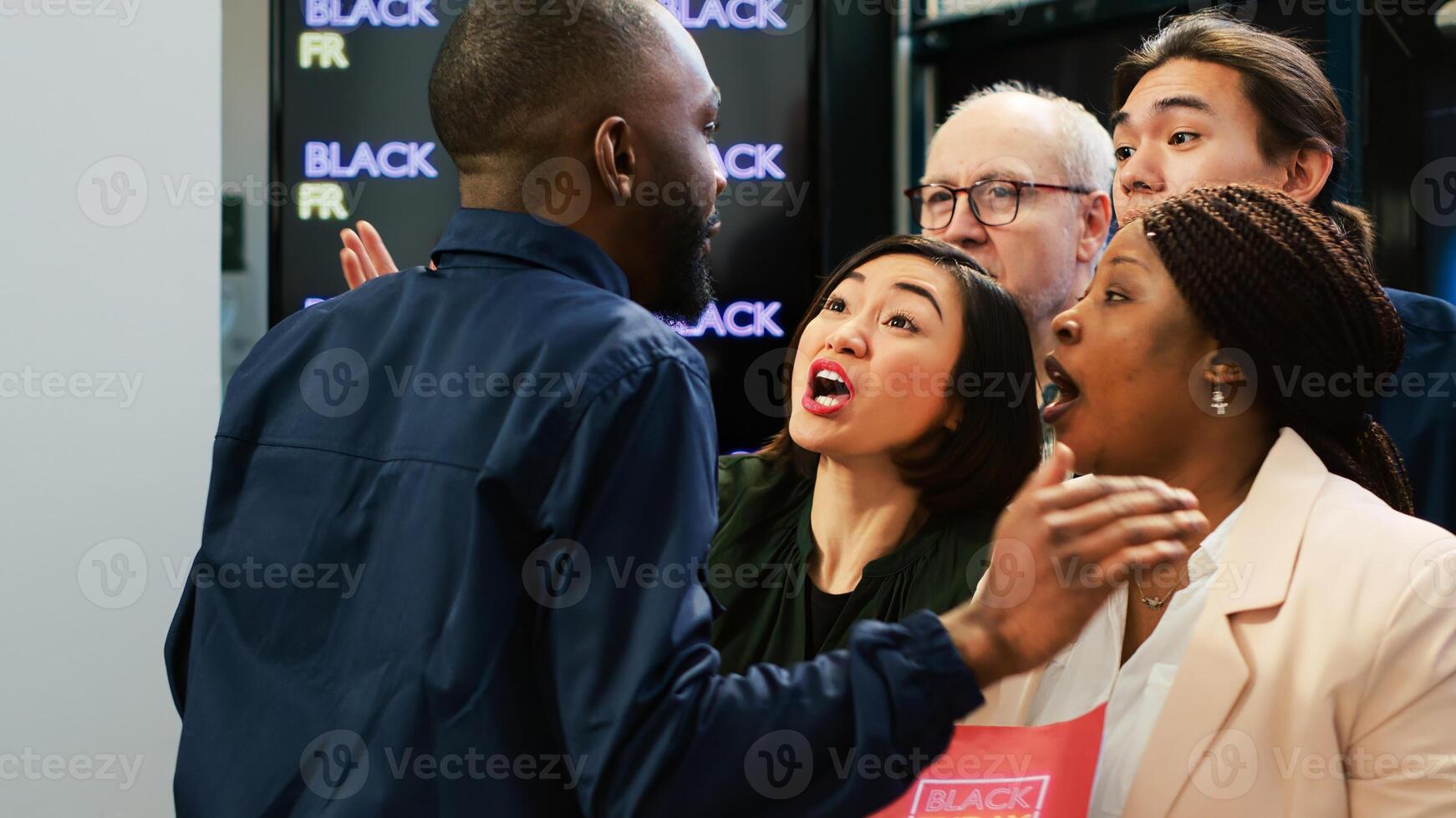 Crazy people breaking store line and pushing security guard to enter clothing retail shop on black friday. Aggressive crowd behind red tape at fashion boutique, big sales. Handheld shot. photo