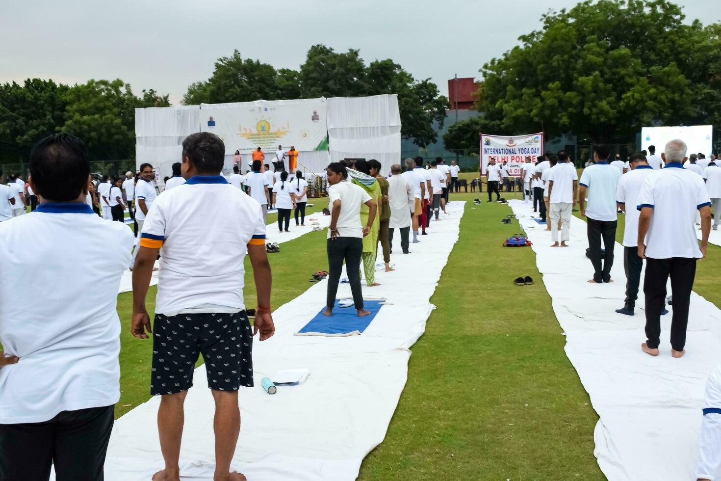 New Delhi, India, June 21, 2023 - Group Yoga exercise session for people at Yamuna Sports Complex in Delhi on International Yoga Day, Big group of adults attending yoga class in cricket stadium photo