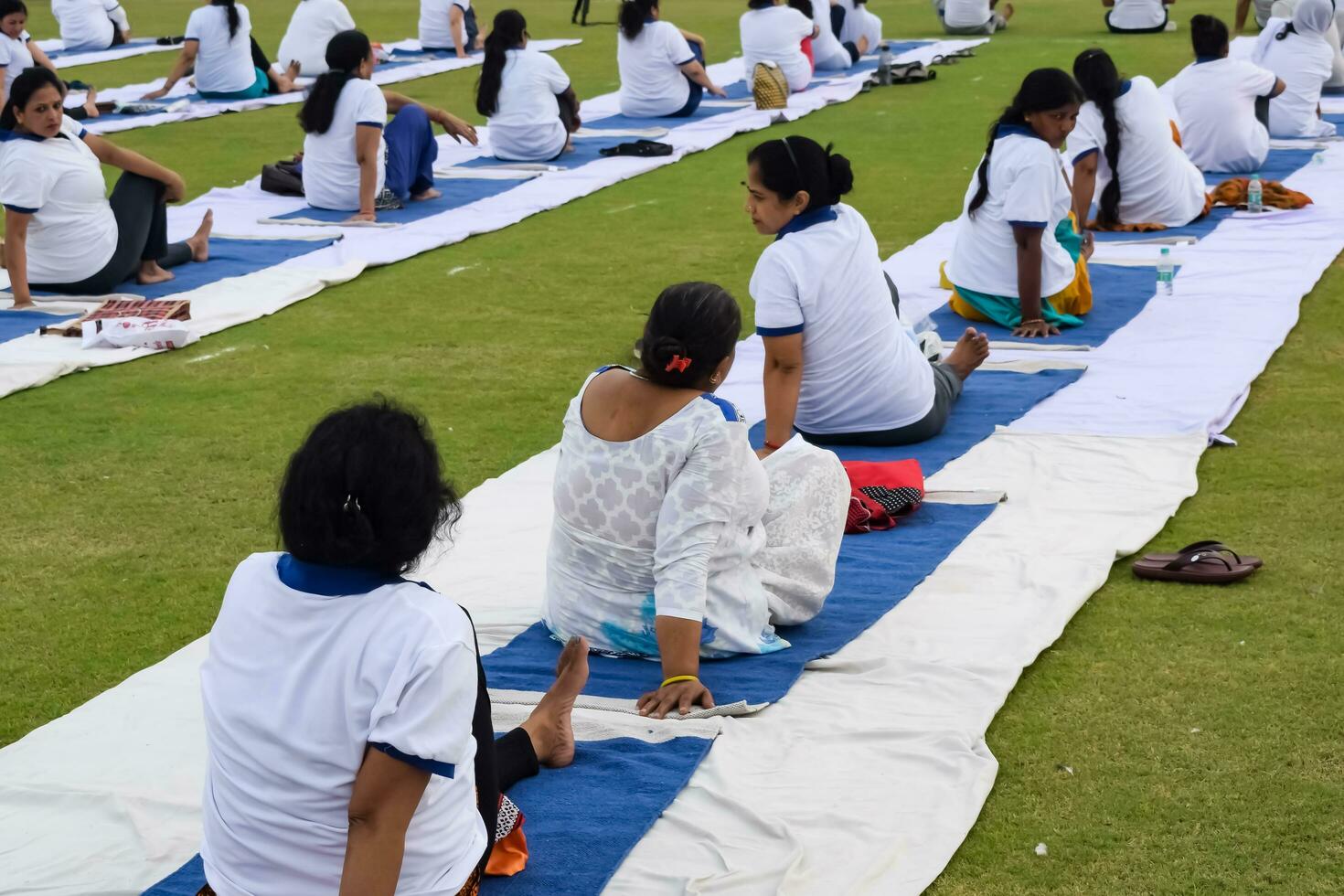 New Delhi, India, June 21, 2023 - Group Yoga exercise session for people at Yamuna Sports Complex in Delhi on International Yoga Day, Big group of adults attending yoga class in cricket stadium photo