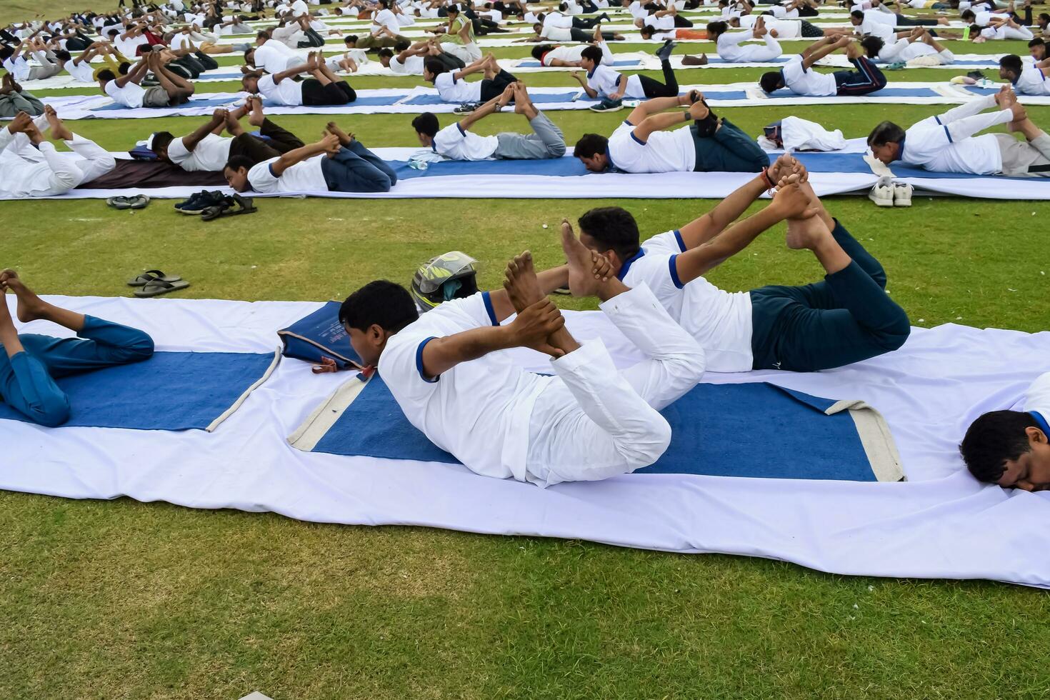 New Delhi, India, June 21, 2023 - Group Yoga exercise session for people at Yamuna Sports Complex in Delhi on International Yoga Day, Big group of adults attending yoga class in cricket stadium photo