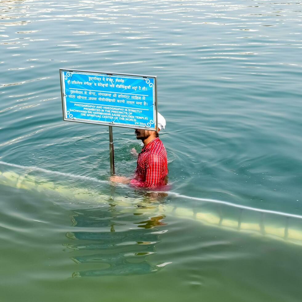 Amritsar, India - February 26 2023 - Unidentified devotees taking holy dip in sarovar at Golden Temple - Harmandir Sahib in Amritsar, Punjab, India, Famous indian sikh landmark, Golden Temple photo