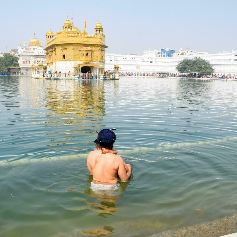 Amritsar, India - February 26 2023 - Unidentified devotees taking holy dip in sarovar at Golden Temple - Harmandir Sahib in Amritsar, Punjab, India, Famous indian sikh landmark, Golden Temple photo