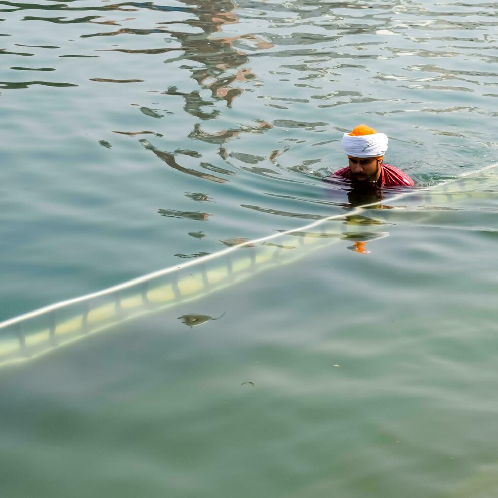 Amritsar, India - February 26 2023 - Unidentified devotees taking holy dip in sarovar at Golden Temple - Harmandir Sahib in Amritsar, Punjab, India, Famous indian sikh landmark, Golden Temple photo