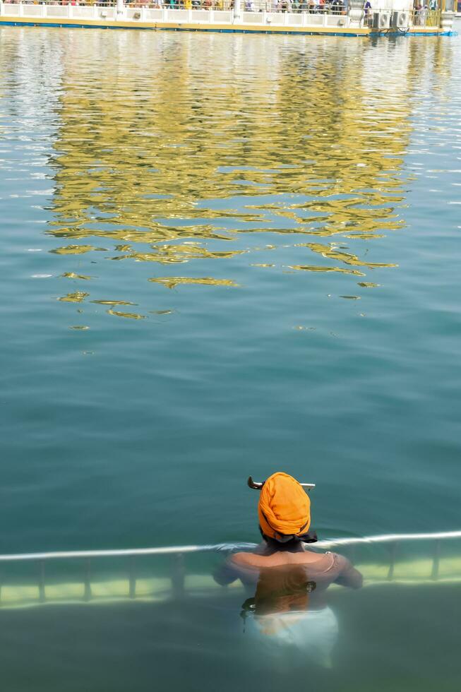 Amritsar, India - February 26 2023 - Unidentified devotees taking holy dip in sarovar at Golden Temple - Harmandir Sahib in Amritsar, Punjab, India, Famous indian sikh landmark, Golden Temple photo
