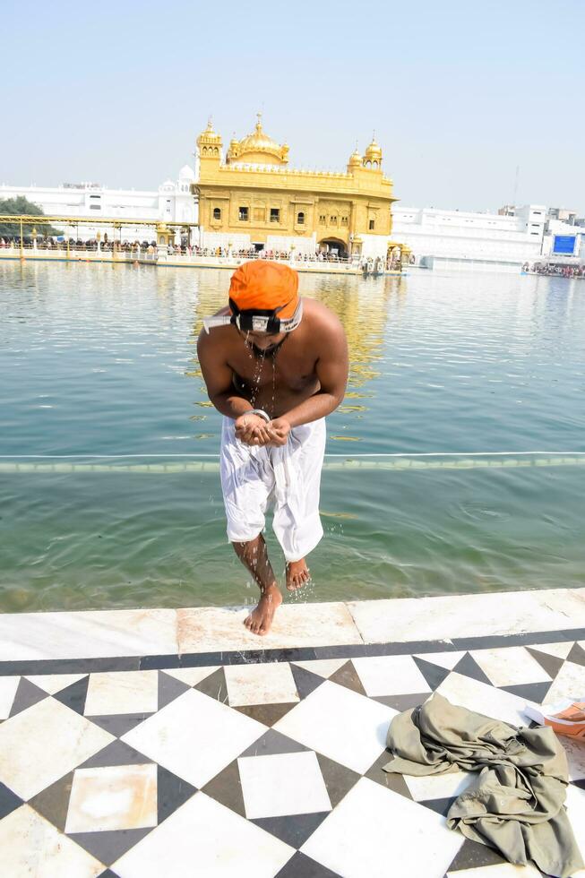 Amritsar, India - February 26 2023 - Unidentified devotees taking holy dip in sarovar at Golden Temple - Harmandir Sahib in Amritsar, Punjab, India, Famous indian sikh landmark, Golden Temple photo