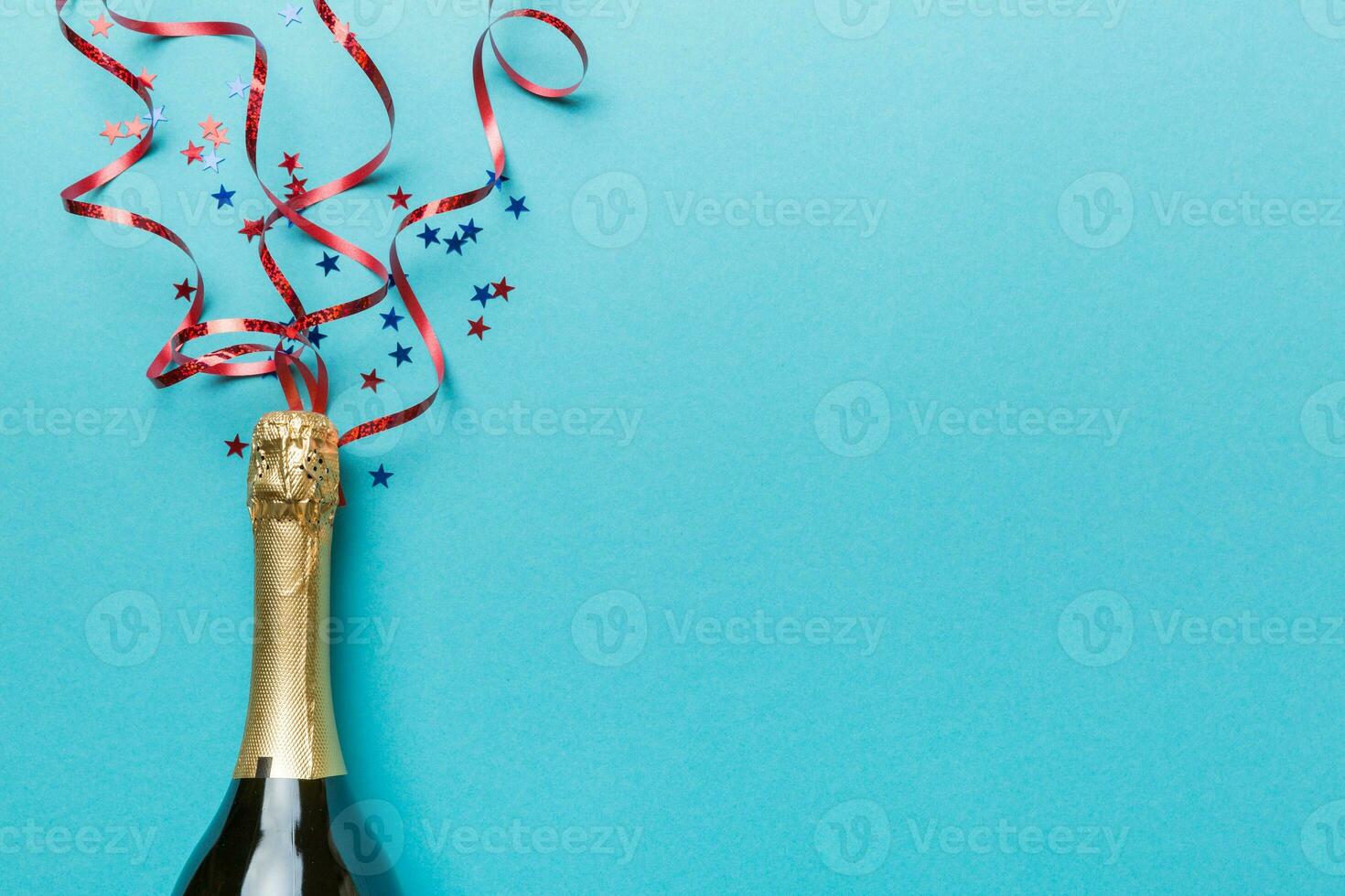 Creative flat lay composition with bottle of champagne and space for text on color background. Champagne bottle with colorful party streamers. holiday or christmas concept photo