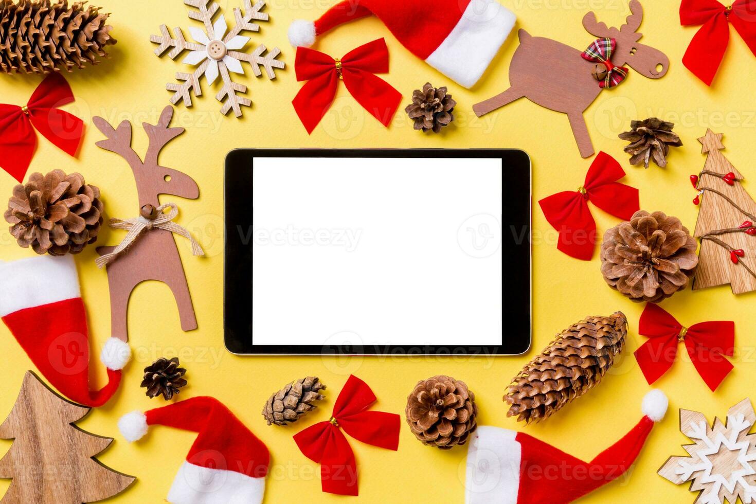 Christmas yellow background with holiday toys and decorations. Top view of digital tablet. Happy New Year concept photo