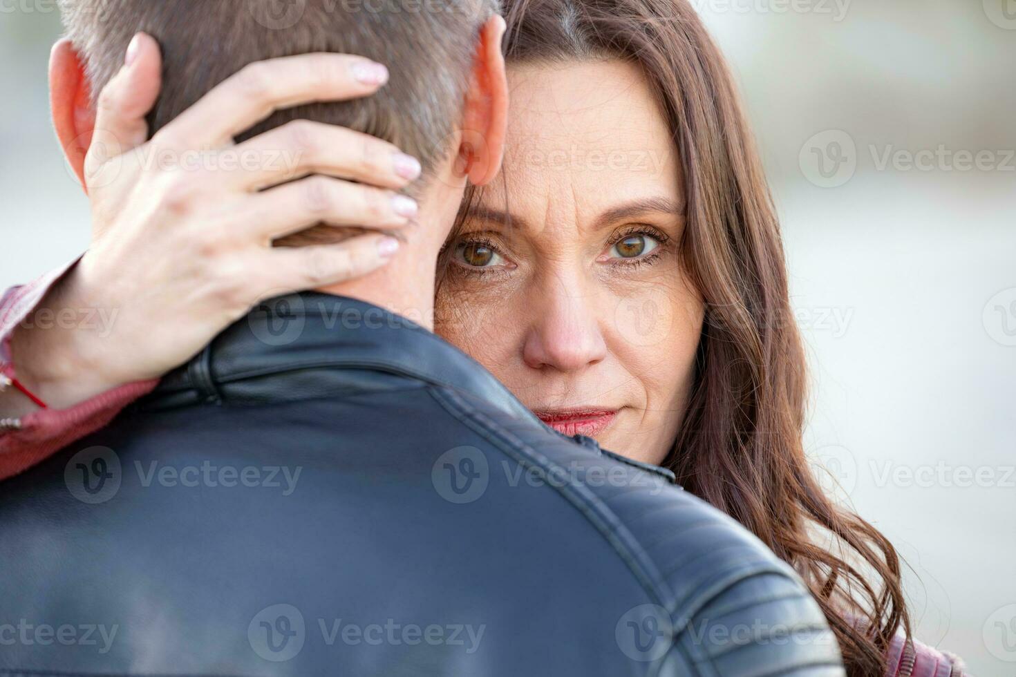 Portrait of a sad woman hugging her boyfriend from behind in the street photo