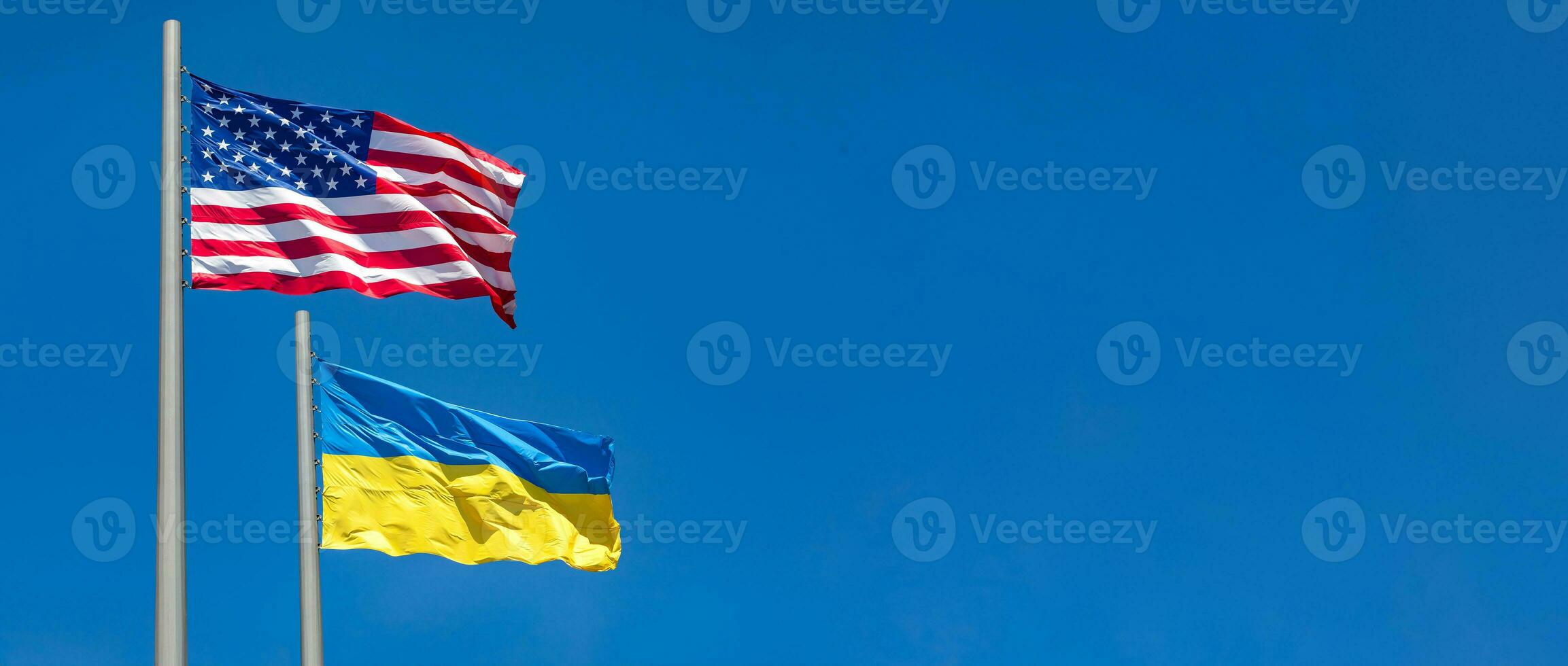 flags of United States and Ukraine waving in the wind against blue sky photo