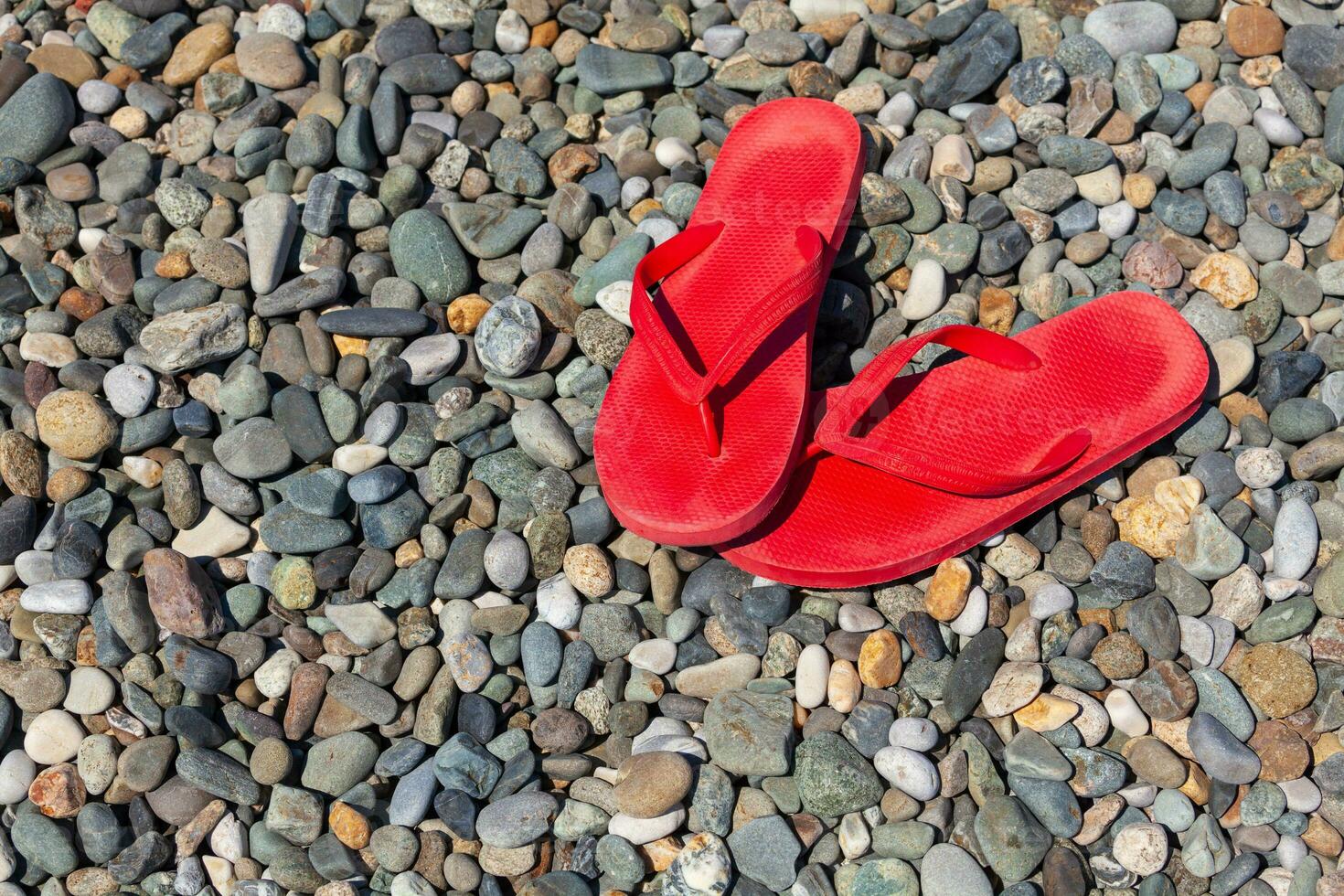 Red flip flops on a pebble beach photo