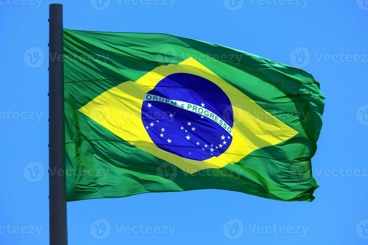 brasileño bandera ondulación en el viento en azul cielo antecedentes. bandera de Brasil. foto