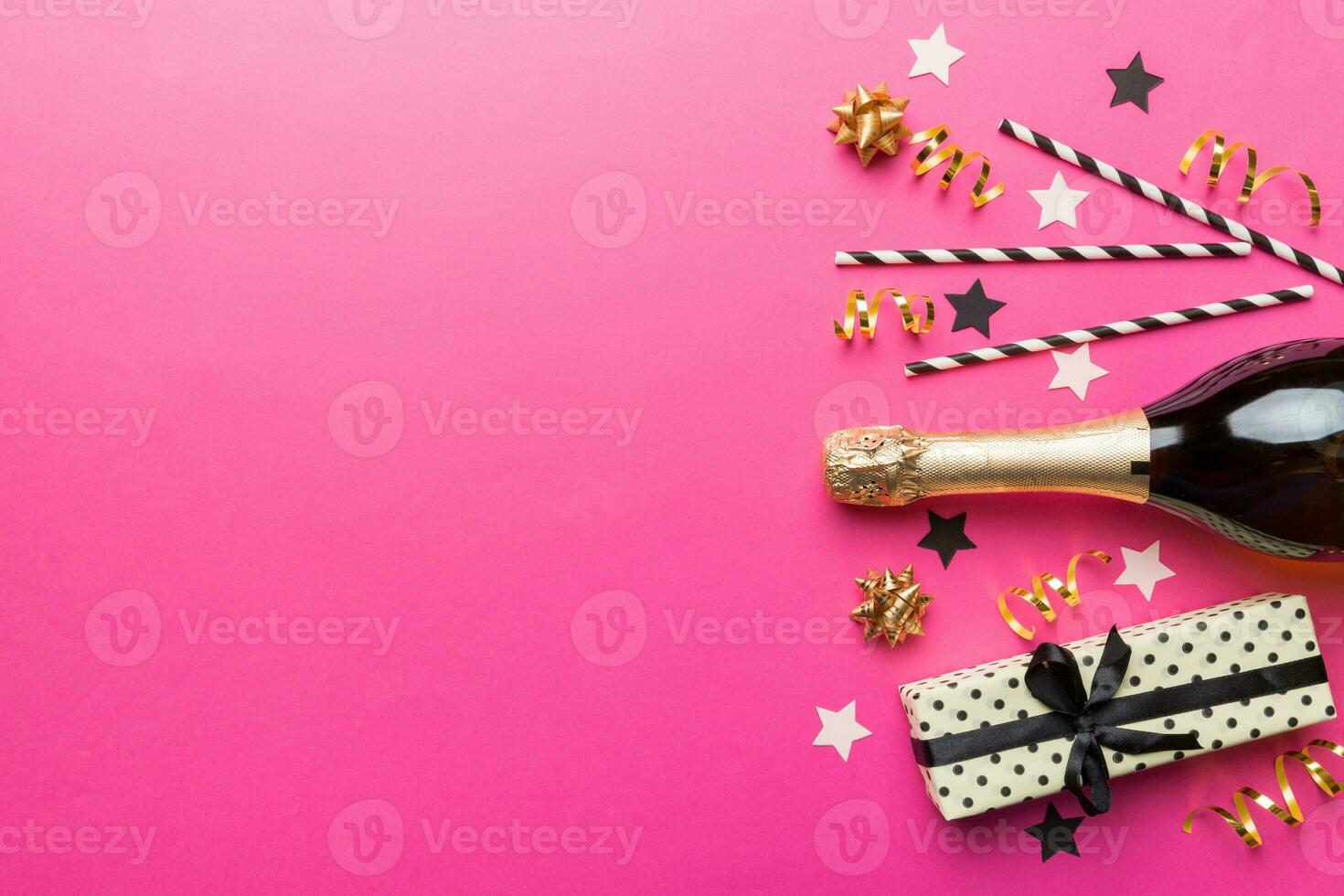 bottle of champagne with glasses and colorful confetti on colored background. top view flay lay photo