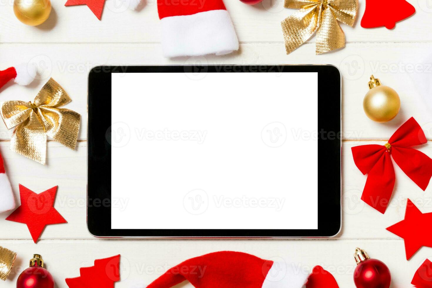 Top view of tablet on holiday wooden background. New Year decorations and toys. Christmas concept photo