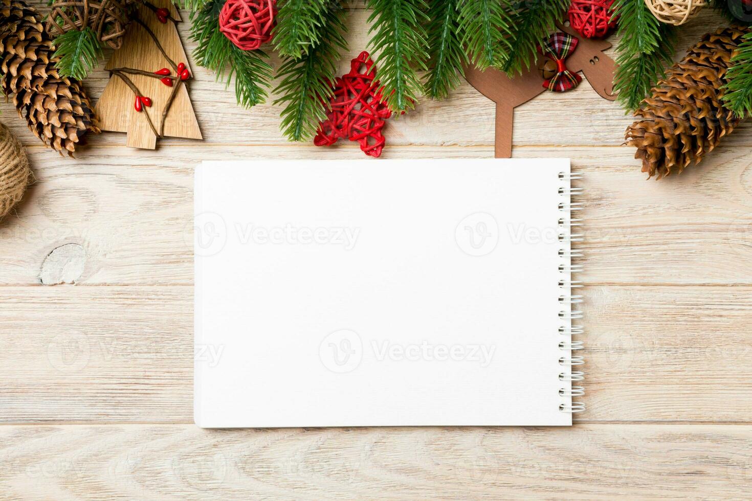 Top view of notebook, Christmas toys, decorations and fir tree branches on wooden background. New Year holiday concept photo