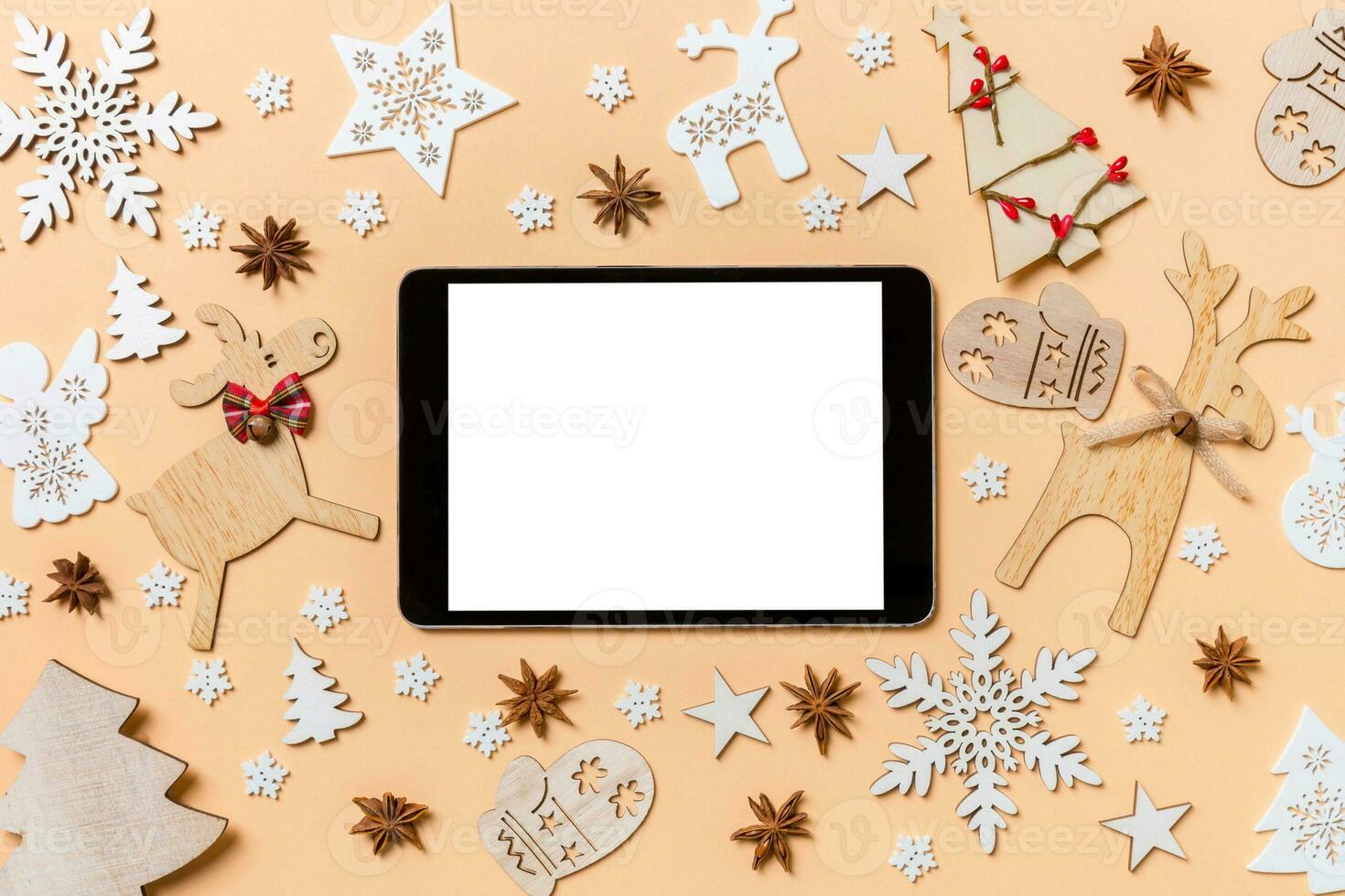 Festive decorations and toys on orange background. Top view of digital tablet. Merry Christmas concept photo