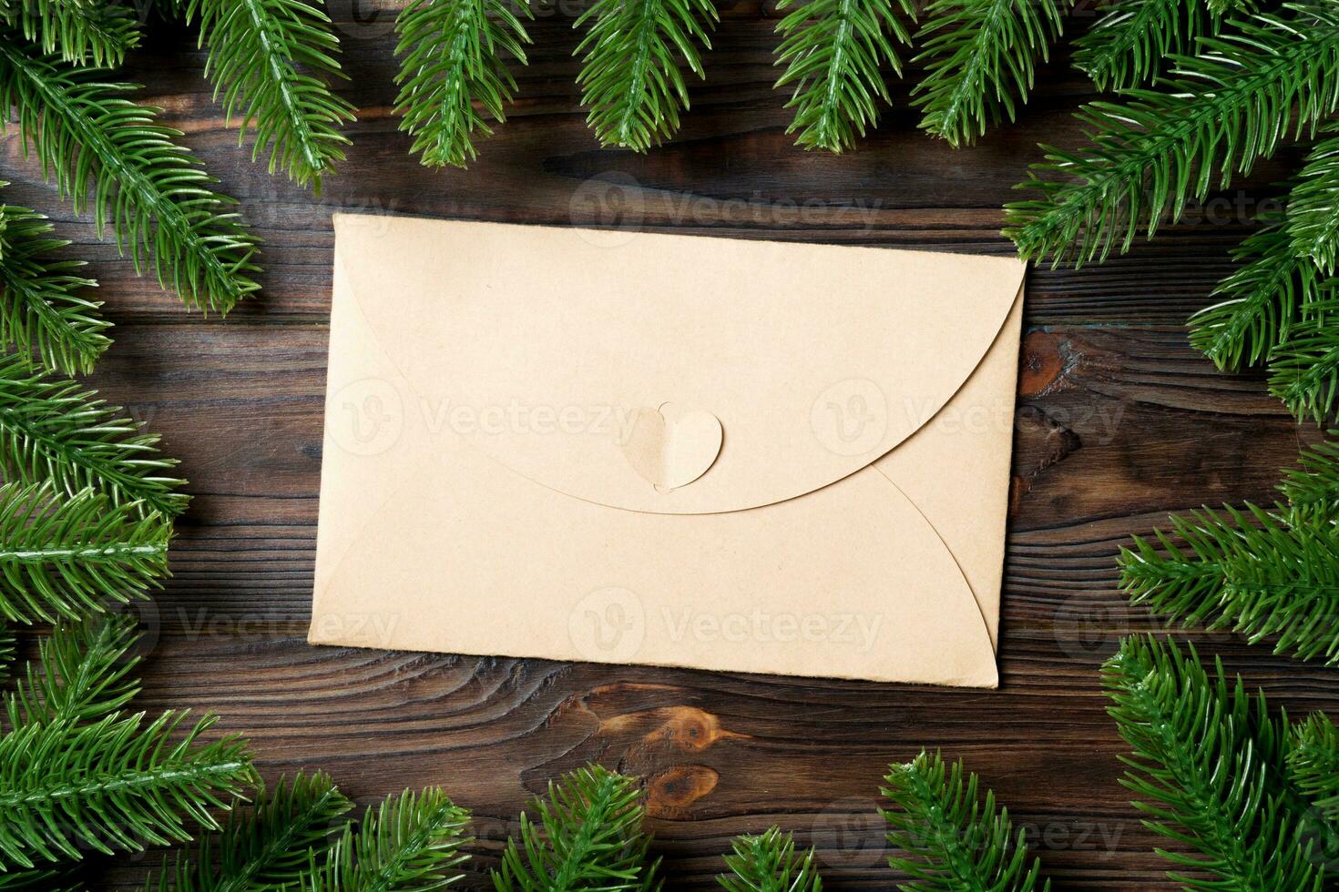 Top view of envelope decorated with a frame made of fir tree on wooden background. New Year time concept photo