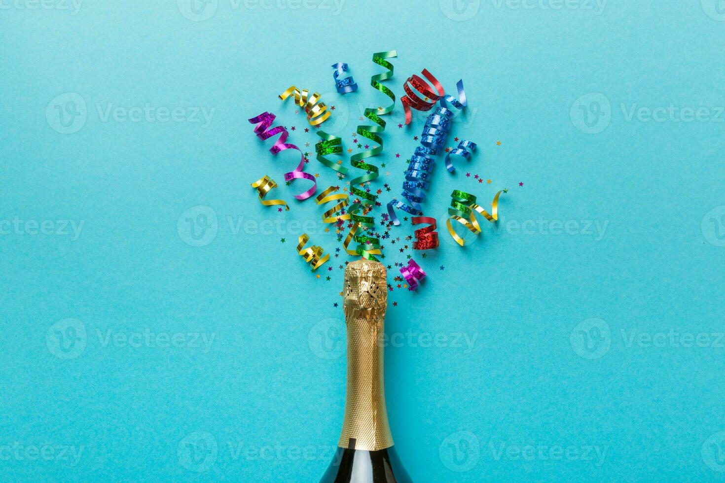 Creative flat lay composition with bottle of champagne and space for text on color background. Champagne bottle with colorful party streamers. holiday or christmas concept photo