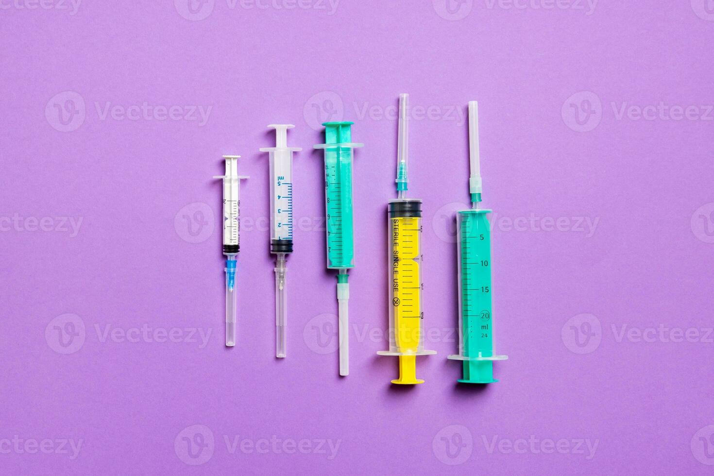 Top view of medical syringes with needles at purple background with copy space. Injection treatment concept photo