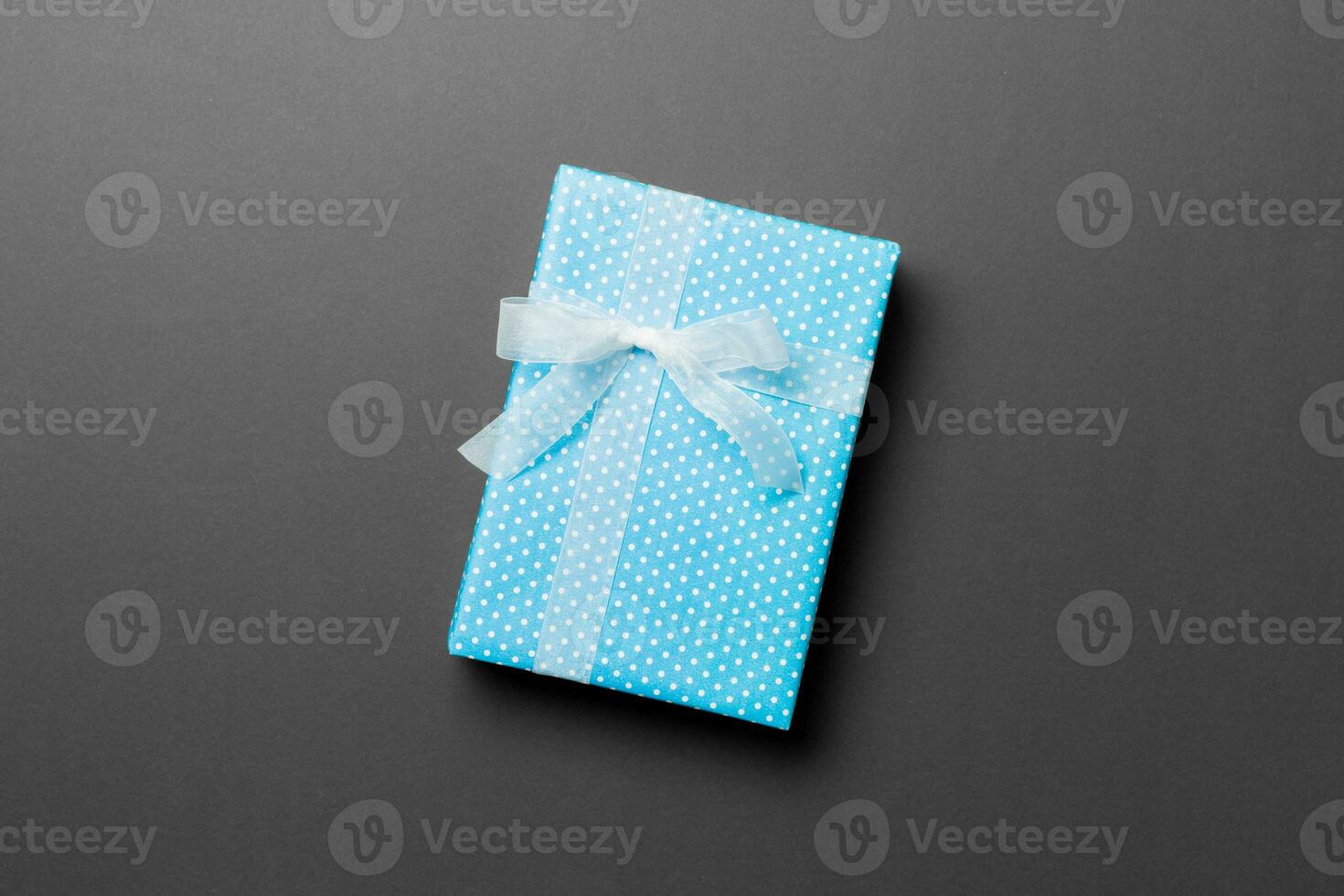 Gift box with white bow for Christmas or New Year day on black background, top view with copy space photo