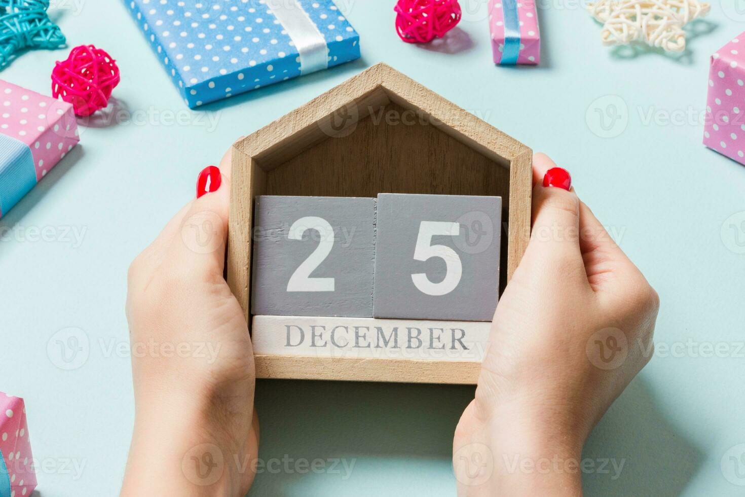 vista superior de las manos femeninas sosteniendo el calendario sobre fondo púrpura. el veinticinco de diciembre. decoraciones navideñas. concepto de tiempo de navidad foto