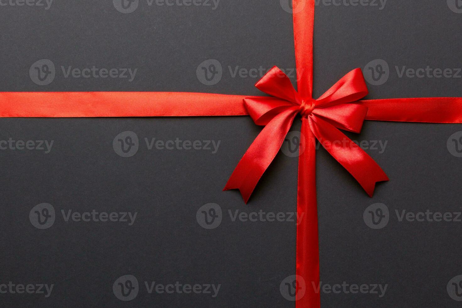 Top view of Red ribbon rolled and red bow isolated on colored background. Flat lay with copy space photo