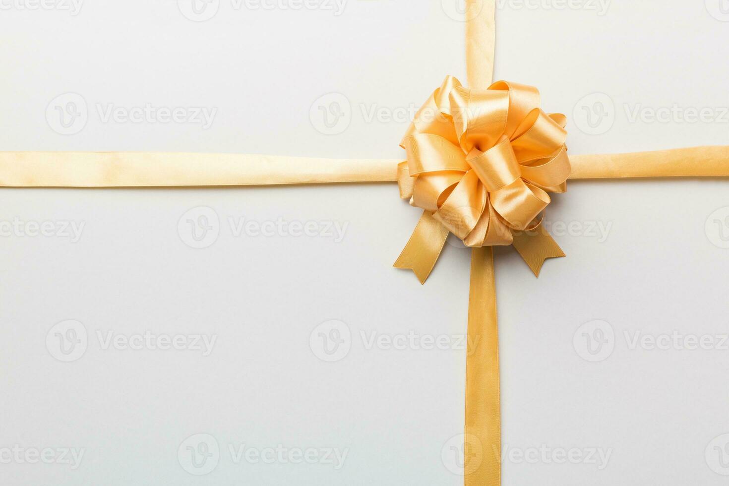 Top view of gold ribbon rolled and yellowbow isolated on colored background. Flat lay with copy space photo