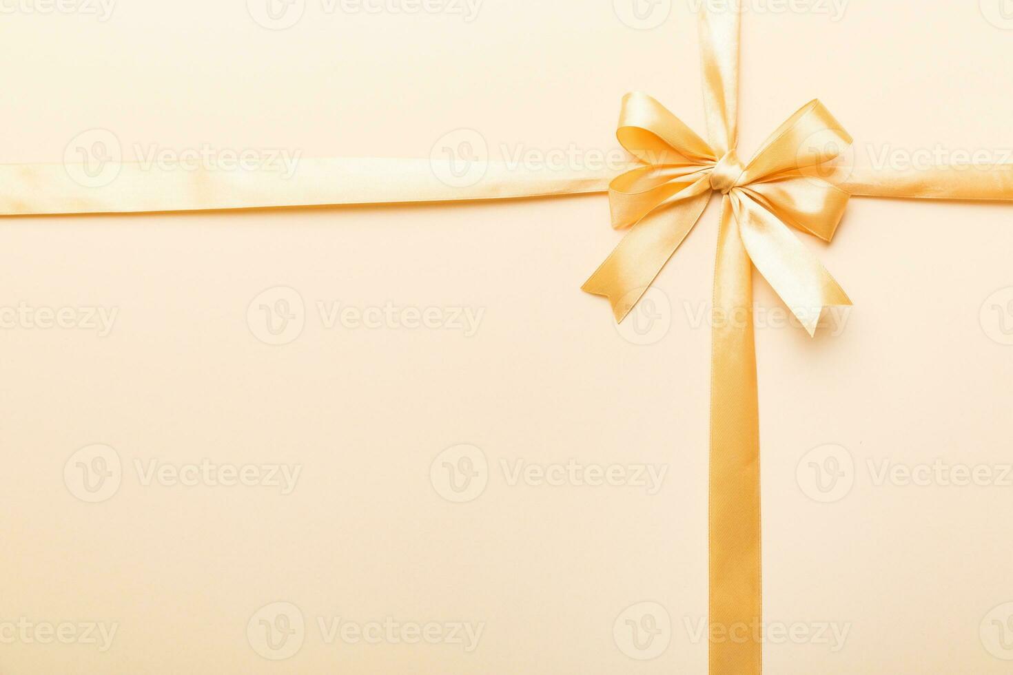 Top view of gold ribbon rolled and yellowbow isolated on colored background. Flat lay with copy space photo