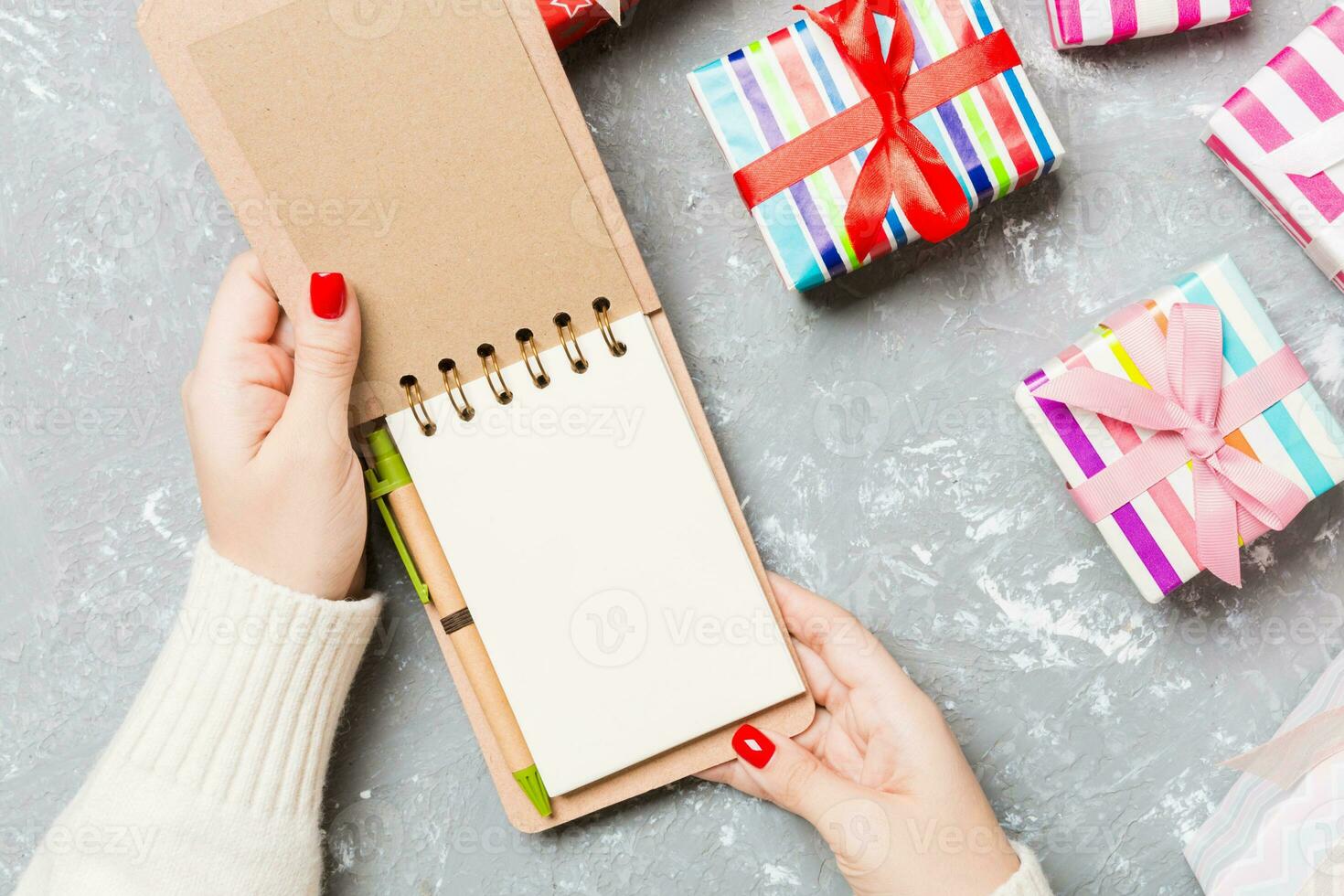 Top view of female hand opening a notebook on cement Christmas background. Wish list. New Year concept photo