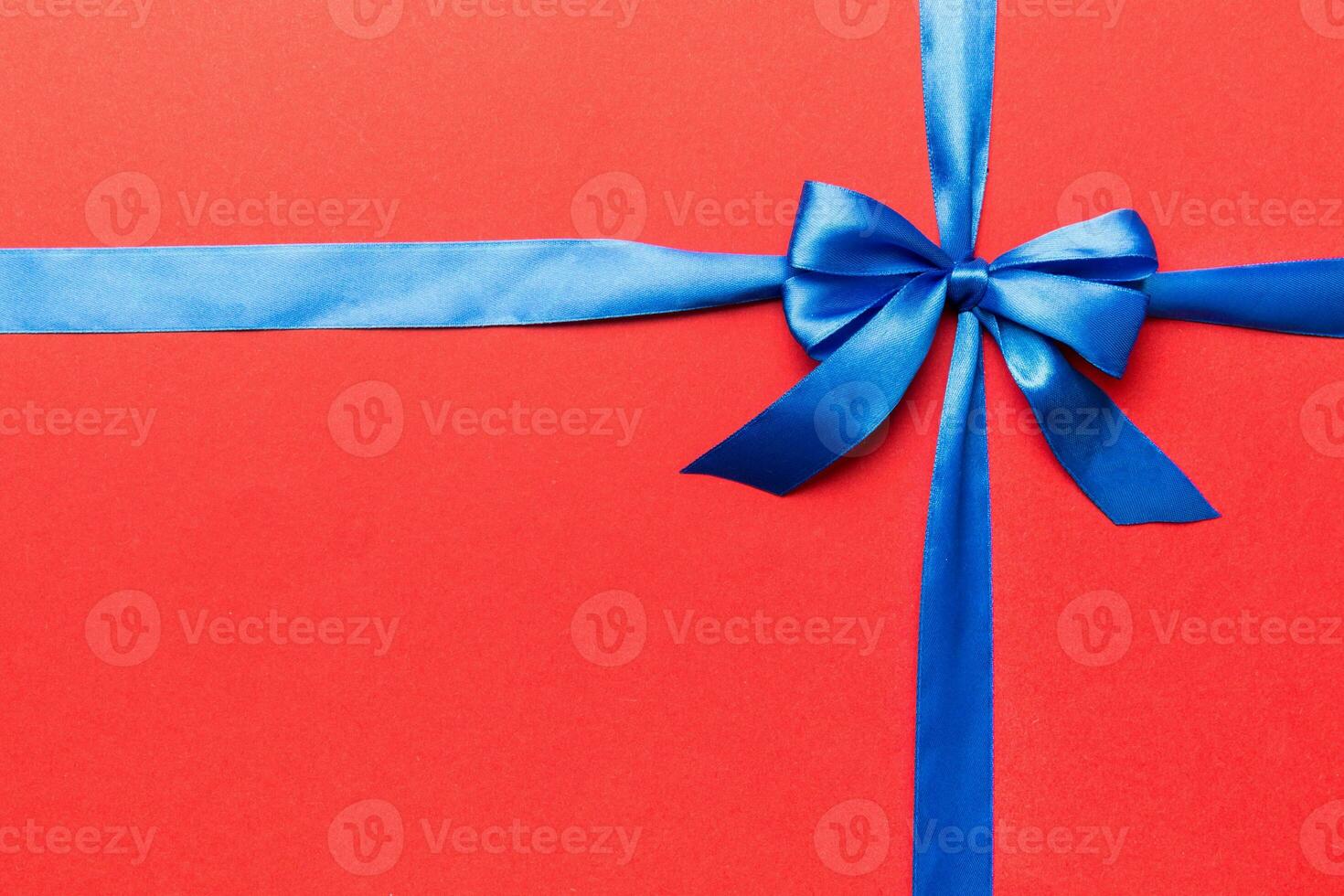 Top view of blue ribbon rolled and blue bow isolated on colored background. Flat lay with copy space photo