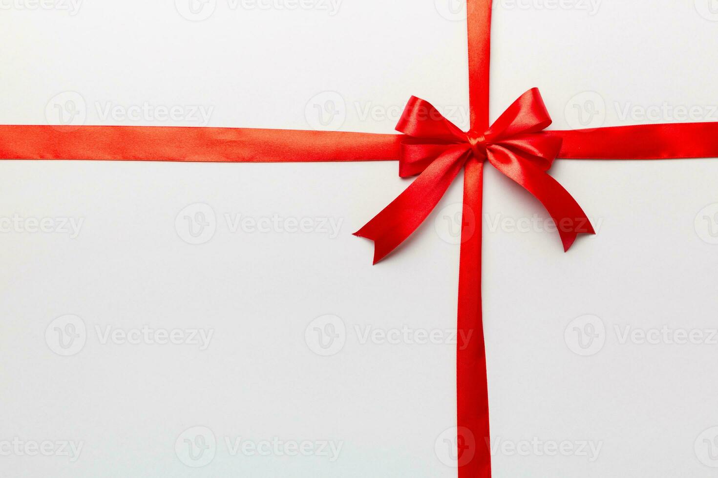 Top view of Red ribbon rolled and red bow isolated on colored background. Flat lay with copy space photo