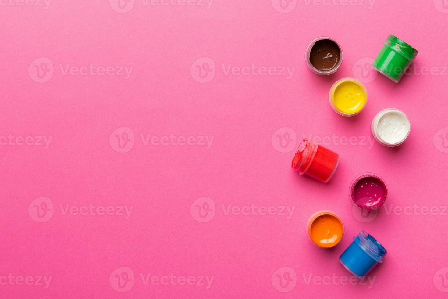 jars with gouache of different colors on Colored background. hobby painting. Top view with empty space. workplace for creativity. home teaching concept drawing photo