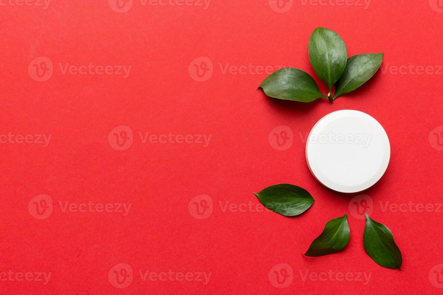 Organic cosmetic product with green leaves on color background. Copy space, flat lay photo