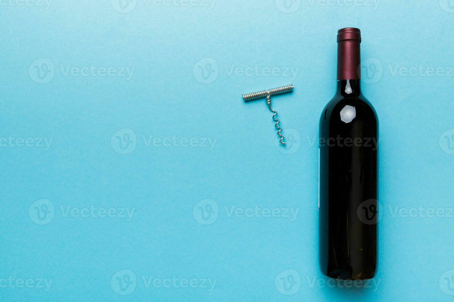 One Bottle of red wine with corkscrew on colored table. Flat lay, top view wth copy space photo