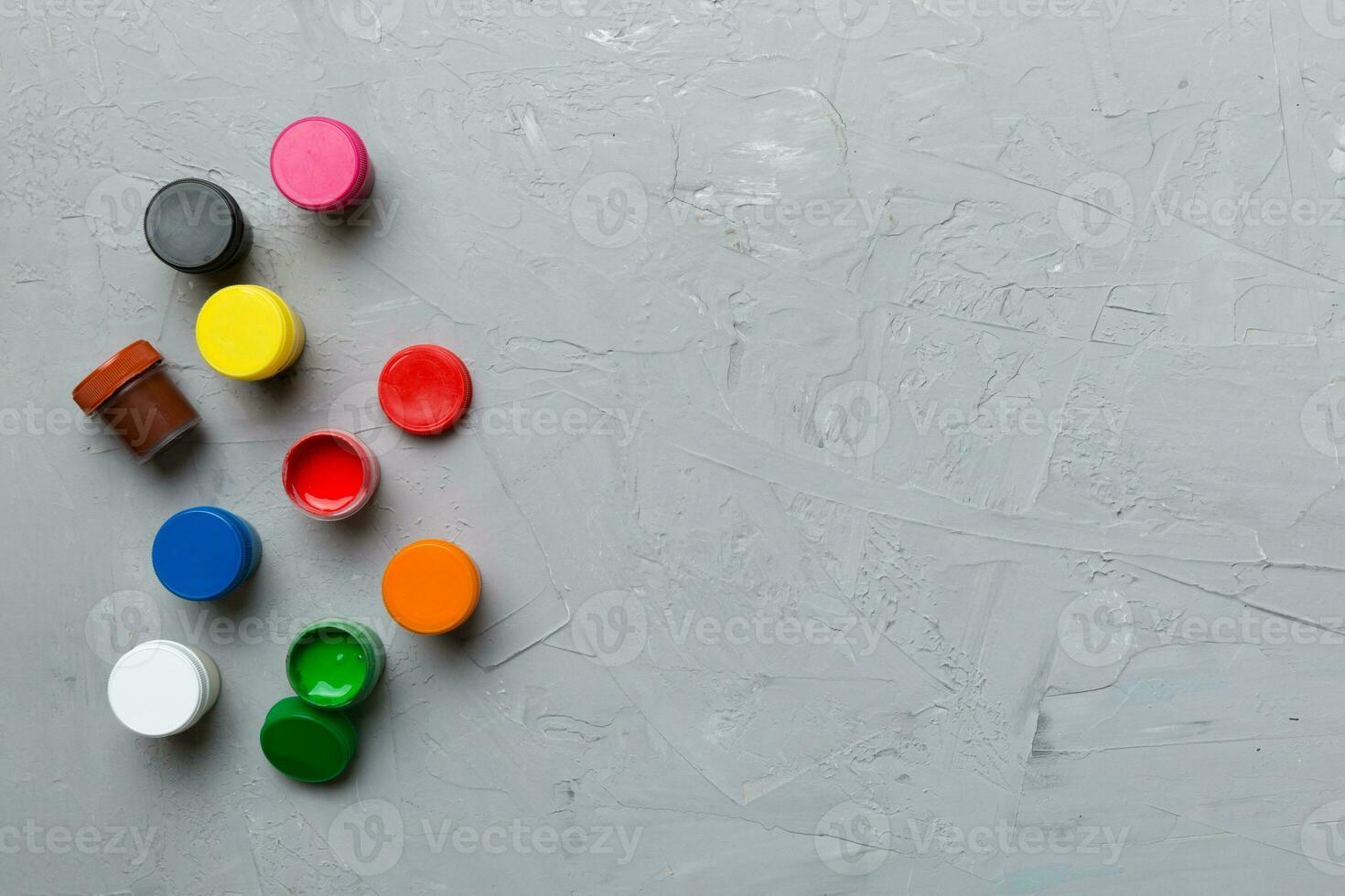 jars with gouache of different colors on Colored background. hobby painting. Top view with empty space. workplace for creativity. home teaching concept drawing photo