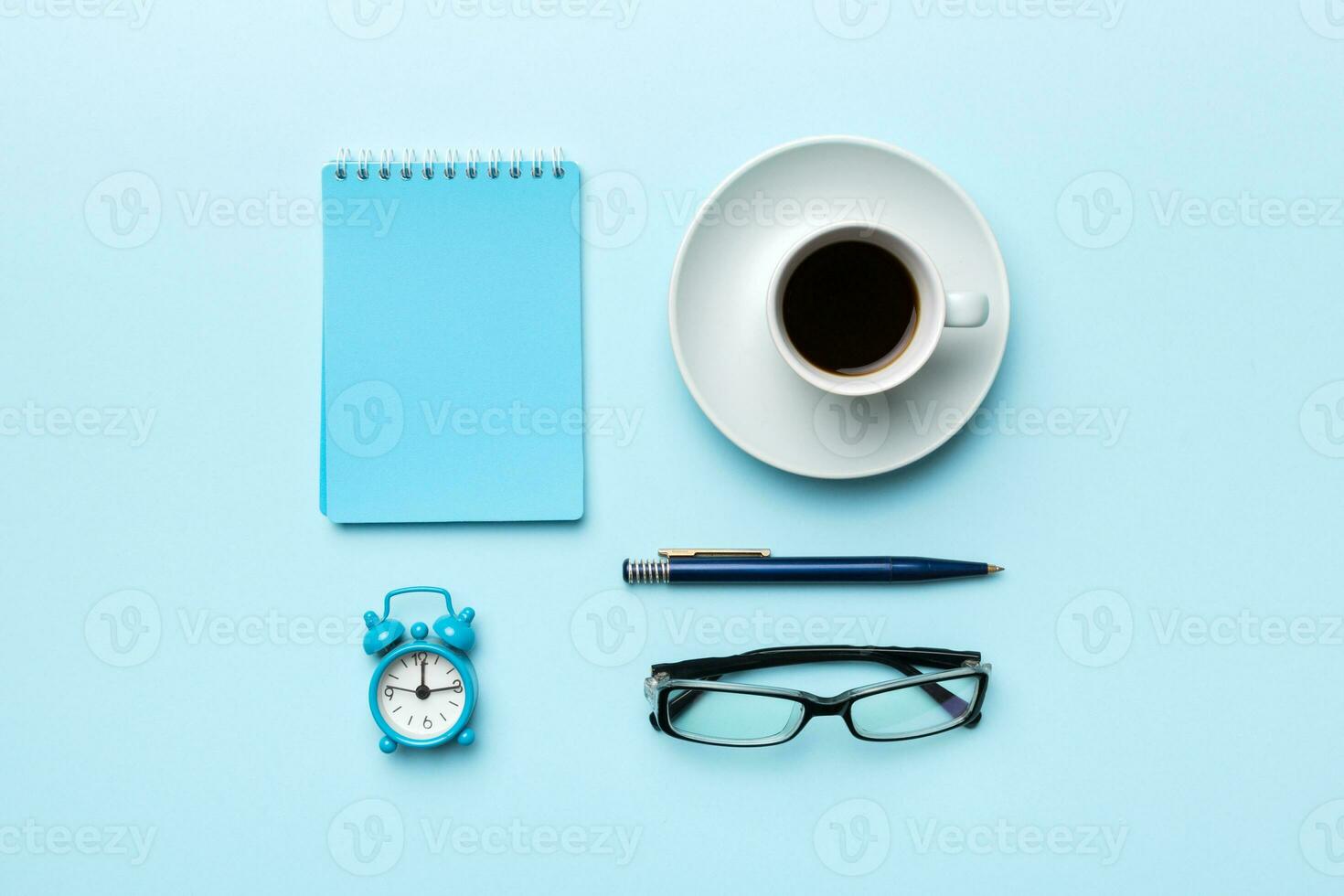 Modern office desk table with notebook and other supplies with cup of coffee. Blank notebook page for you design. Top view, flat lay photo